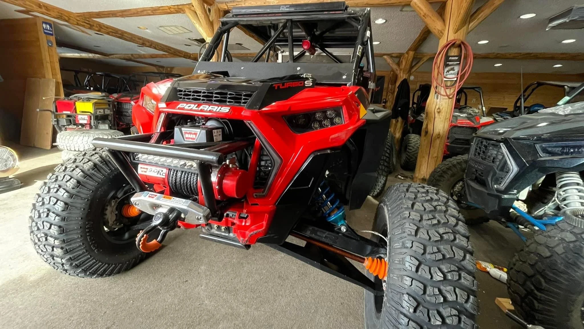 A red Polaris off-road vehicle in a showroom with other off-road vehicles in the background.