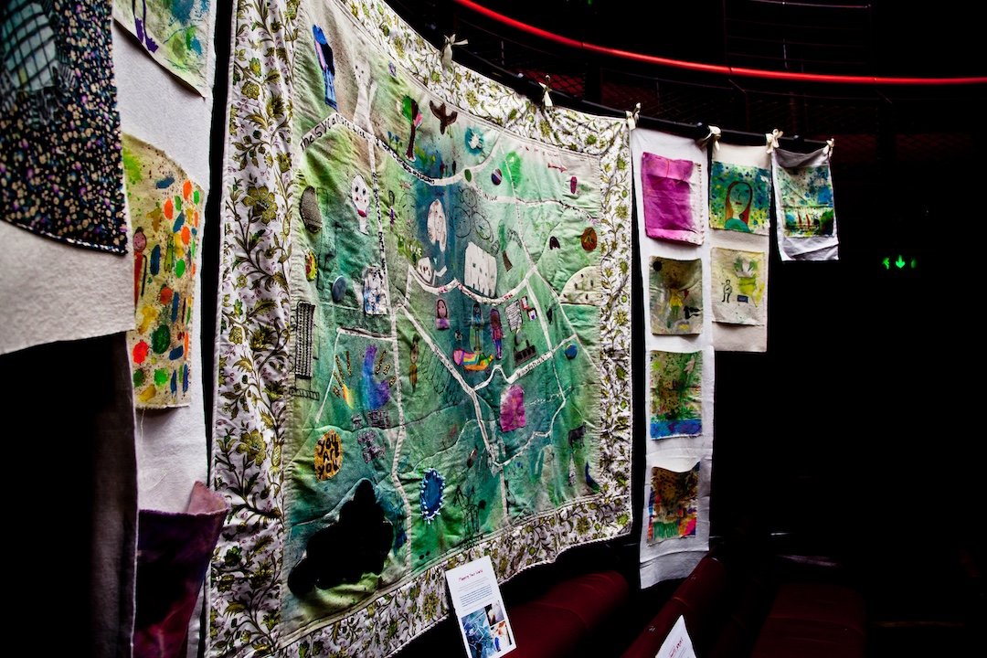 The finished textile piece on display at The Egg Theatre in Bath. The piece shows a map of the children's home village, exploring concepts of home & identity