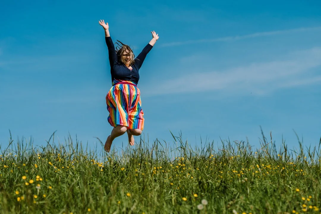 Woman joyfully jumps in the air wearing a rainbow dress, intro to 33 ways to play