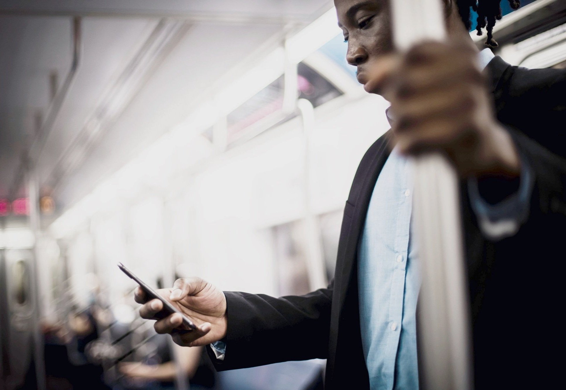  A business person on the metro, checking his phone. 