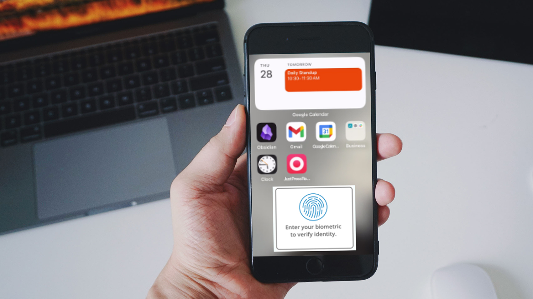  A person holding an iPhone, the home screen has apps and biometric verification to log in to the app. 