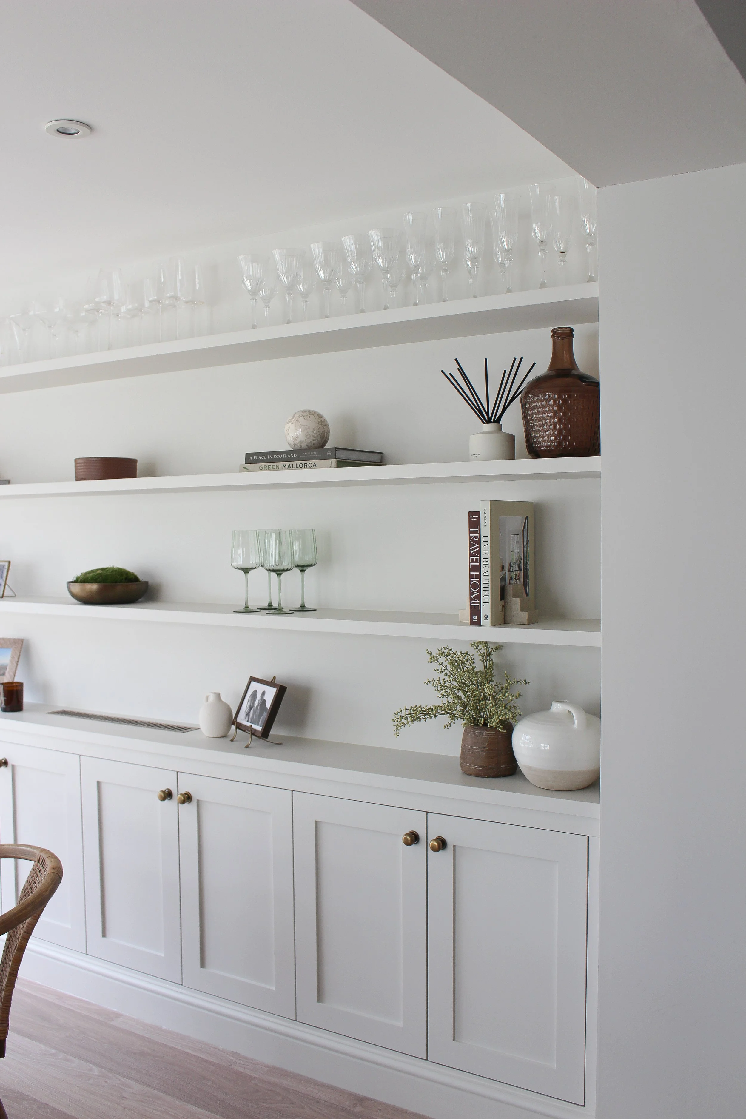 White built-in bookshelf with decorative items including glasses, vases, books, and plants.