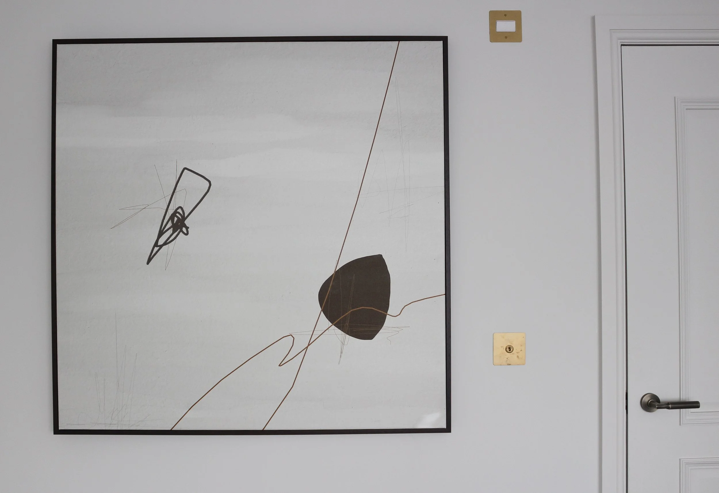 Abstract art piece hanging on a white wall, featuring black lines, a dark brown shape, and copper coloured lines. Master bedroom designed by Yazzmin Lovelle Interiors