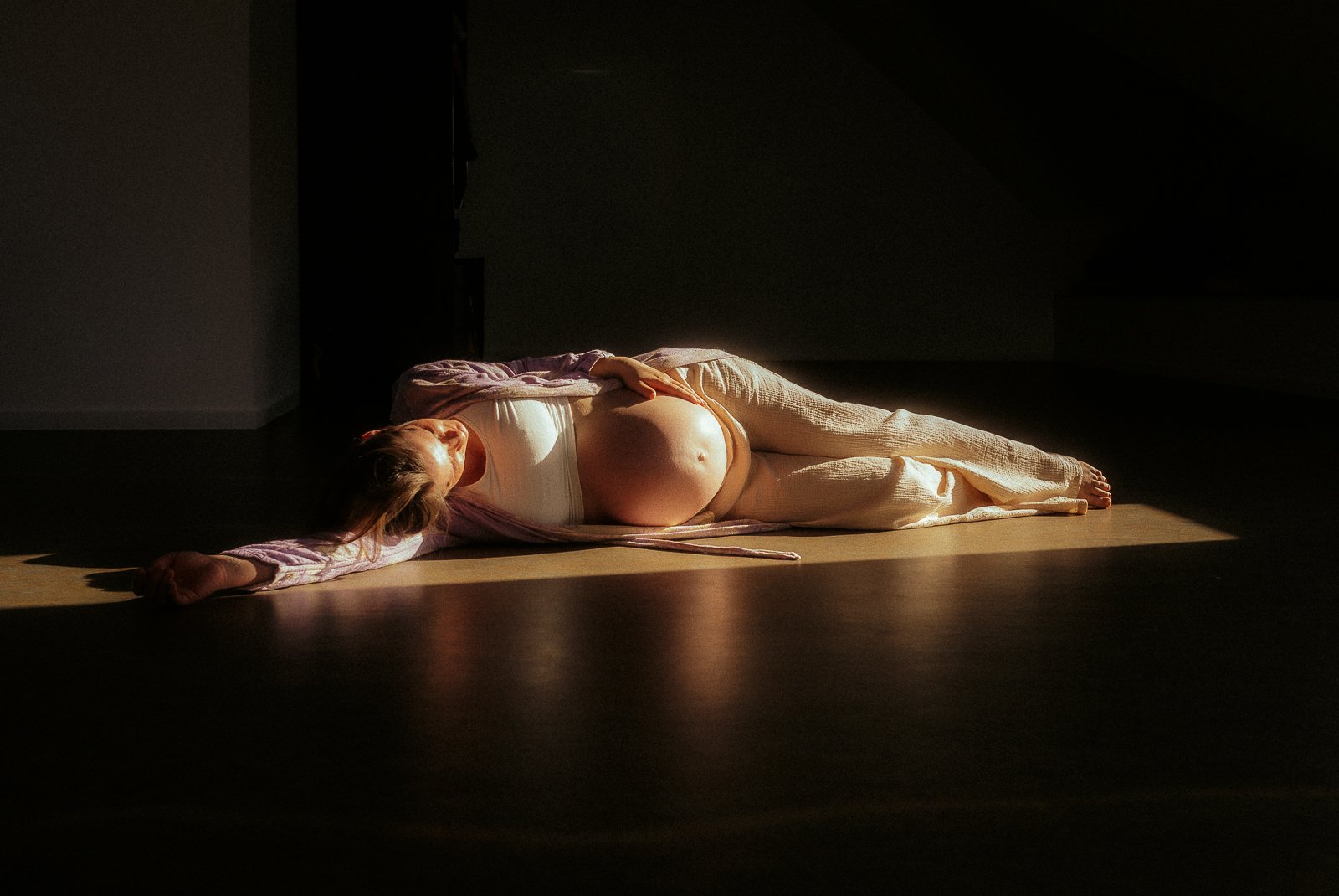Schwangere Frau im Studio sinnlich auf dem Boden liegend; natürliche Fotografie in Melle & Osnabrück