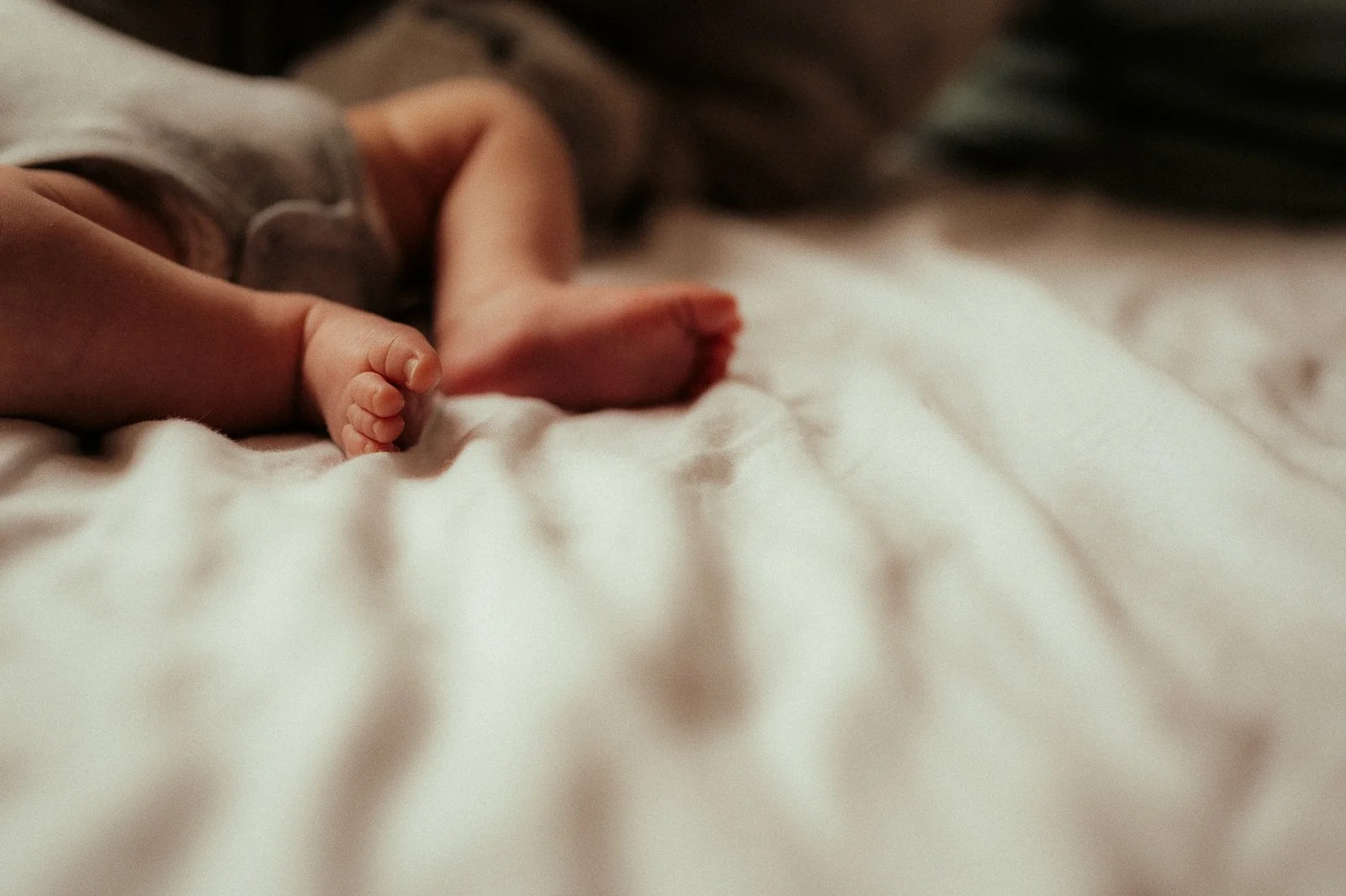 Baby liegt auf einer Decke; Babyfüße ; natürliche Babyfotografie