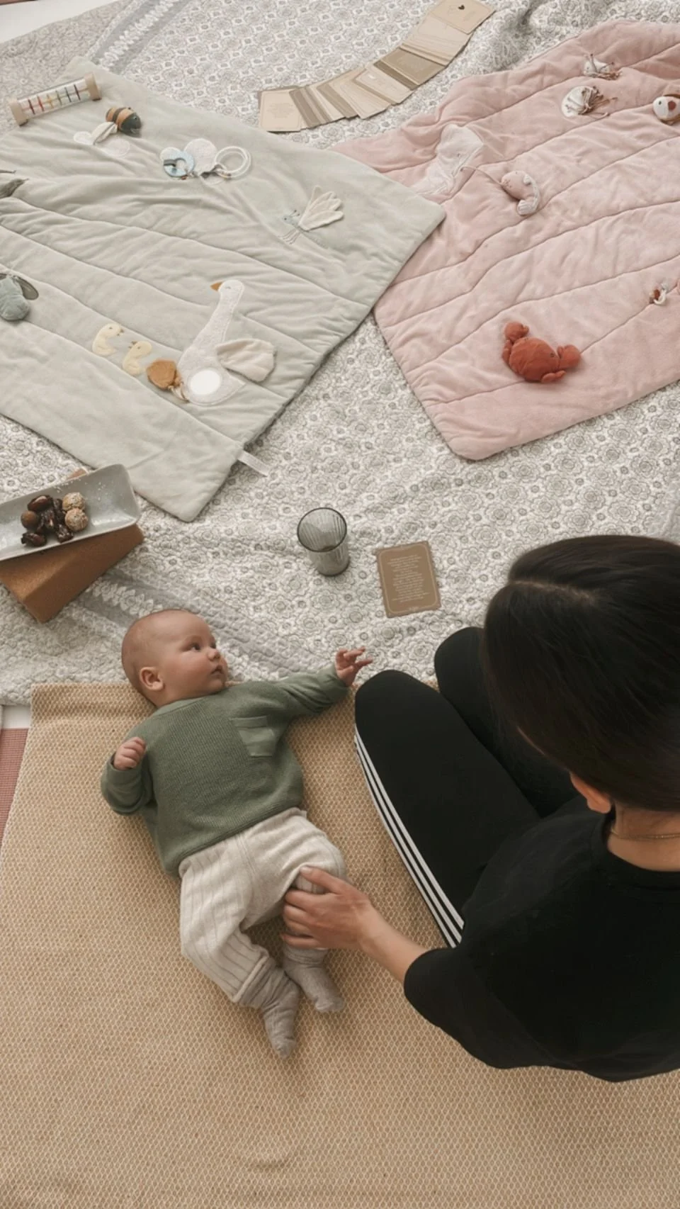 Mama und Baby im vorbereiteten Kursraum mit Krabbeldecken und Kursutensilien
