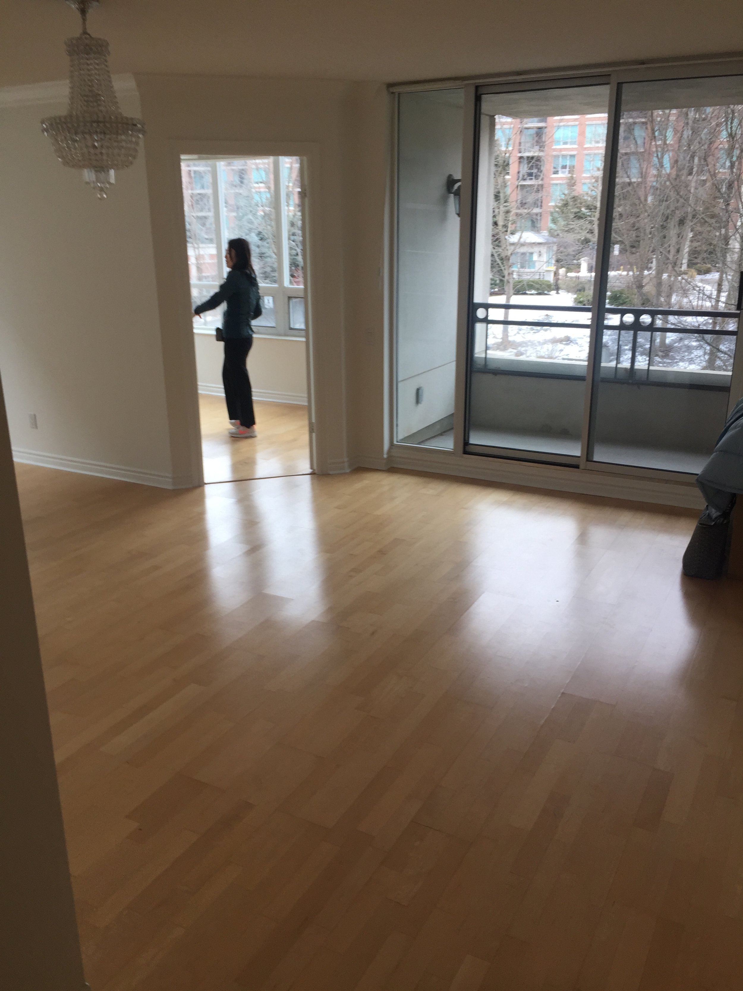 The before look of a condo renovation, old flooring with a wall and balcony