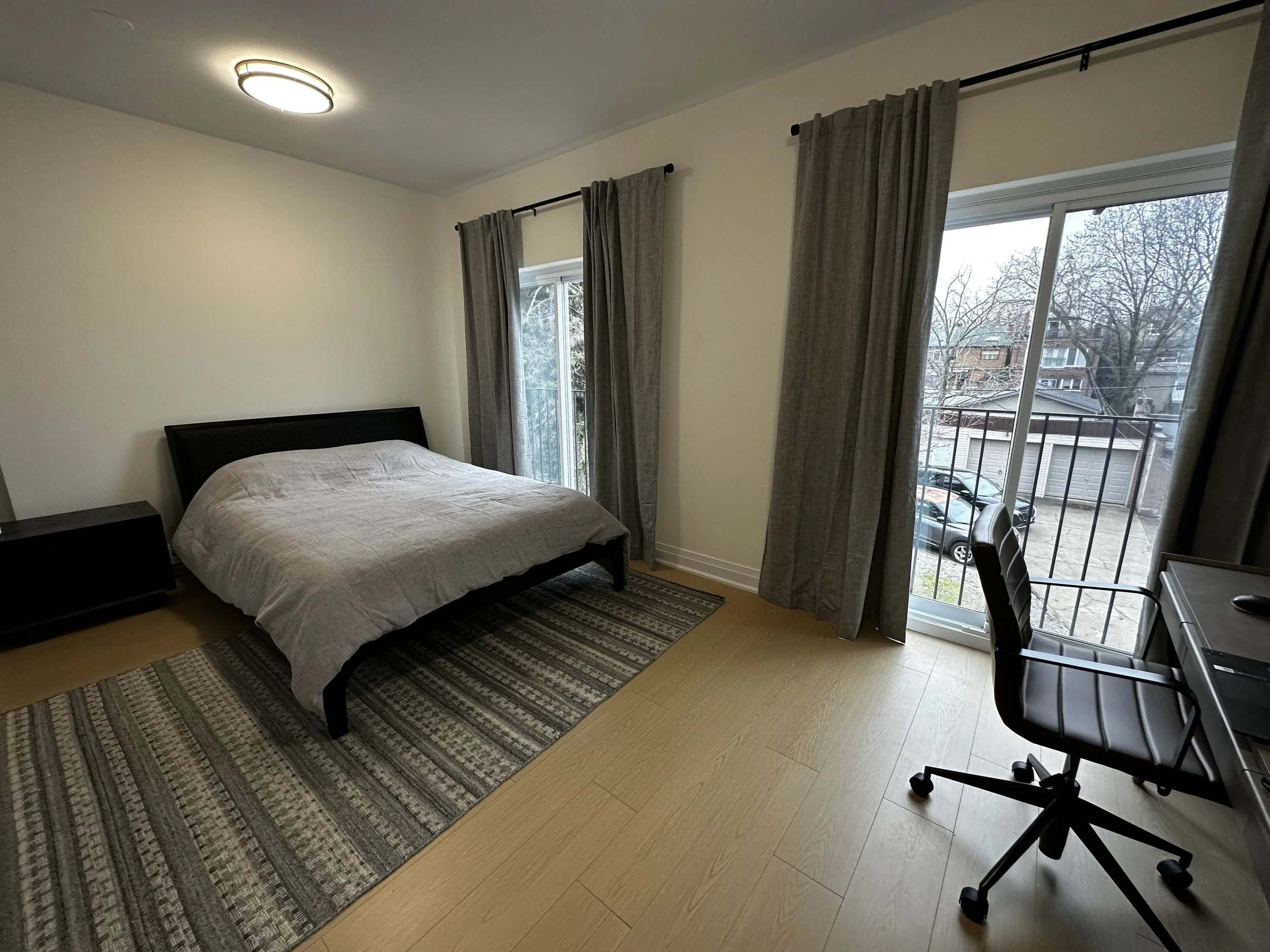 Renovated bedroom with large curtains and office space