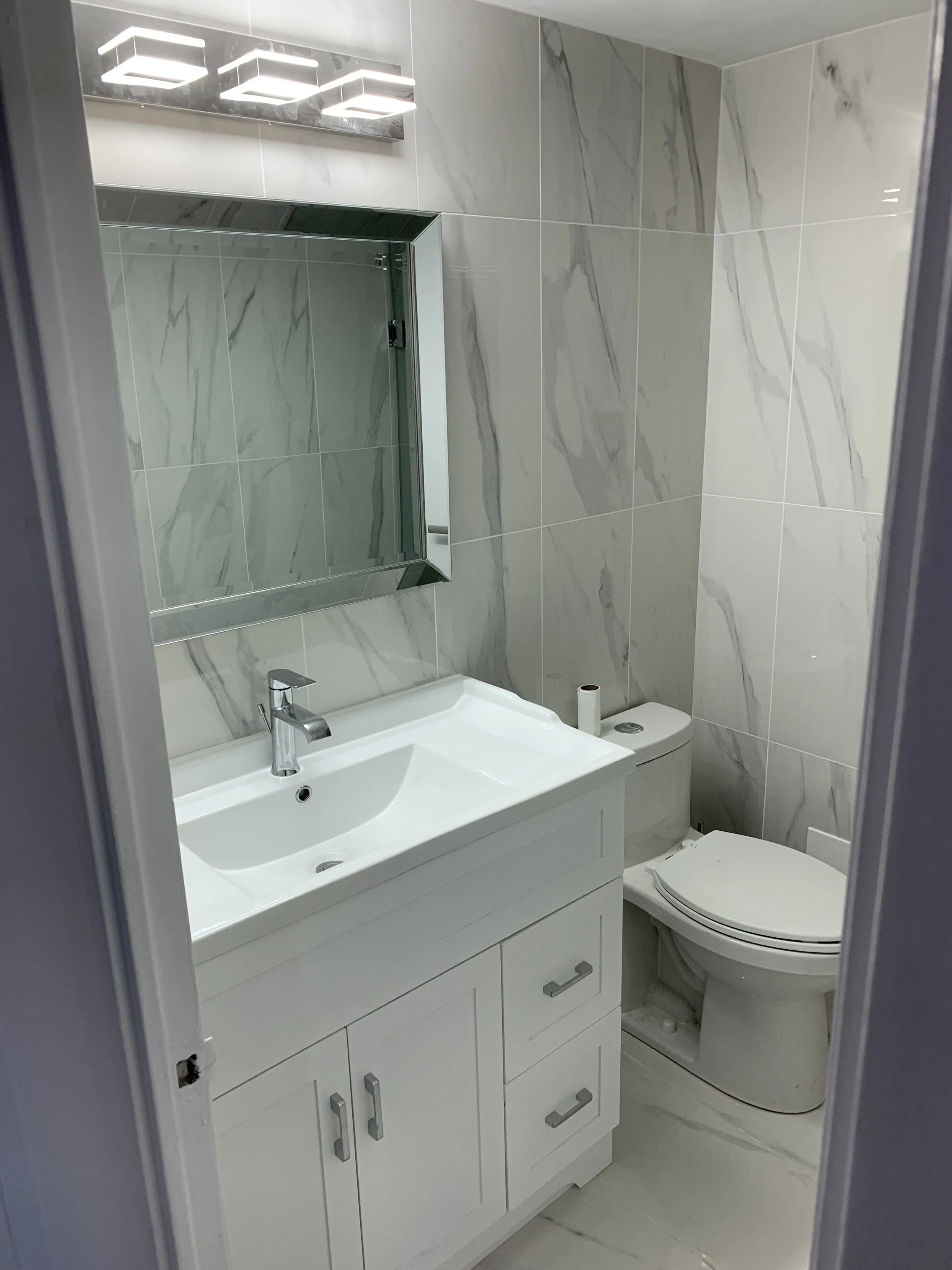 Purely white bathroom with a new vanity, mirror, and toilet