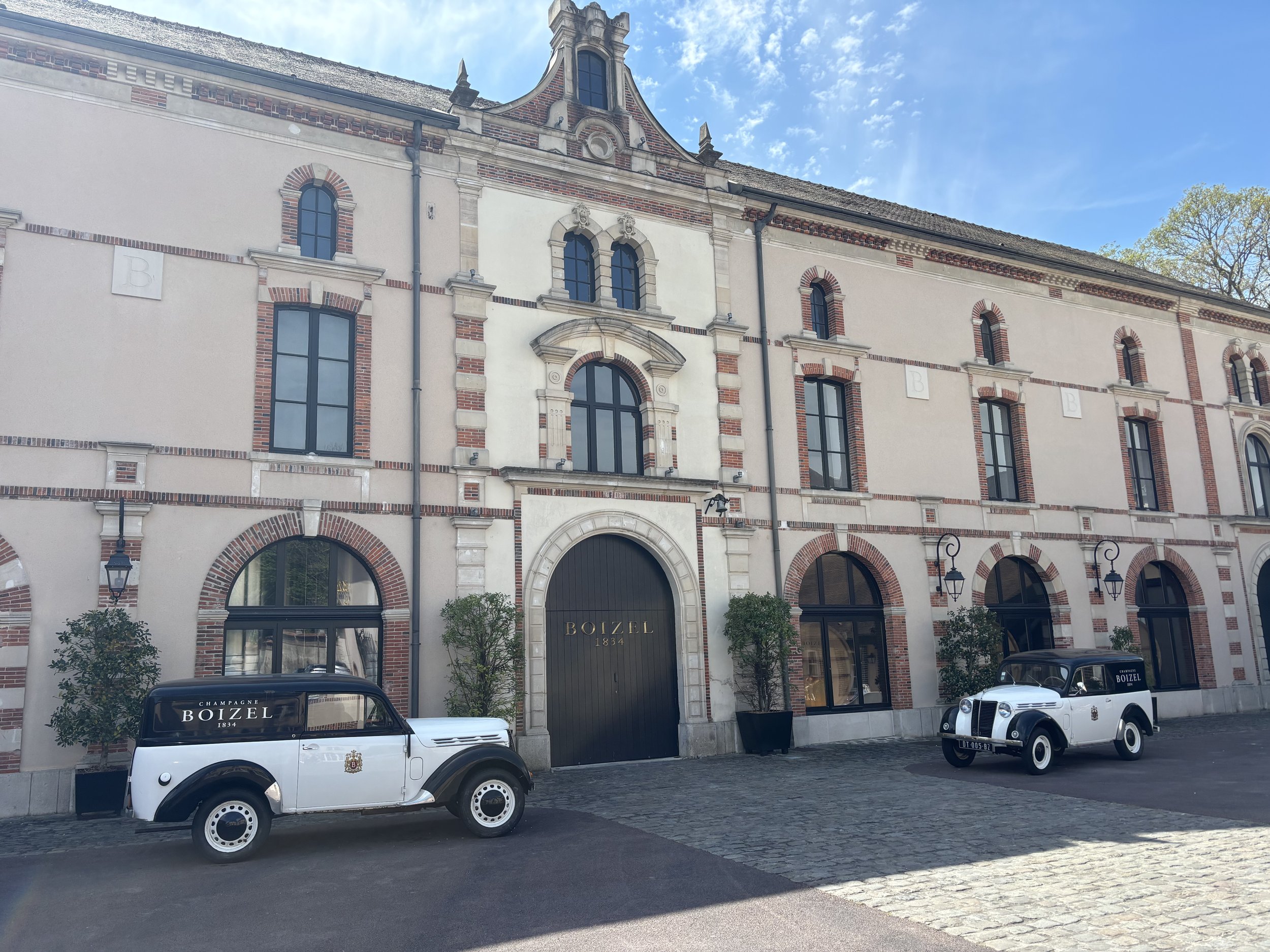Two vintage Boizel champagne delivery vans parked outside the historic Boizel champagne house facade