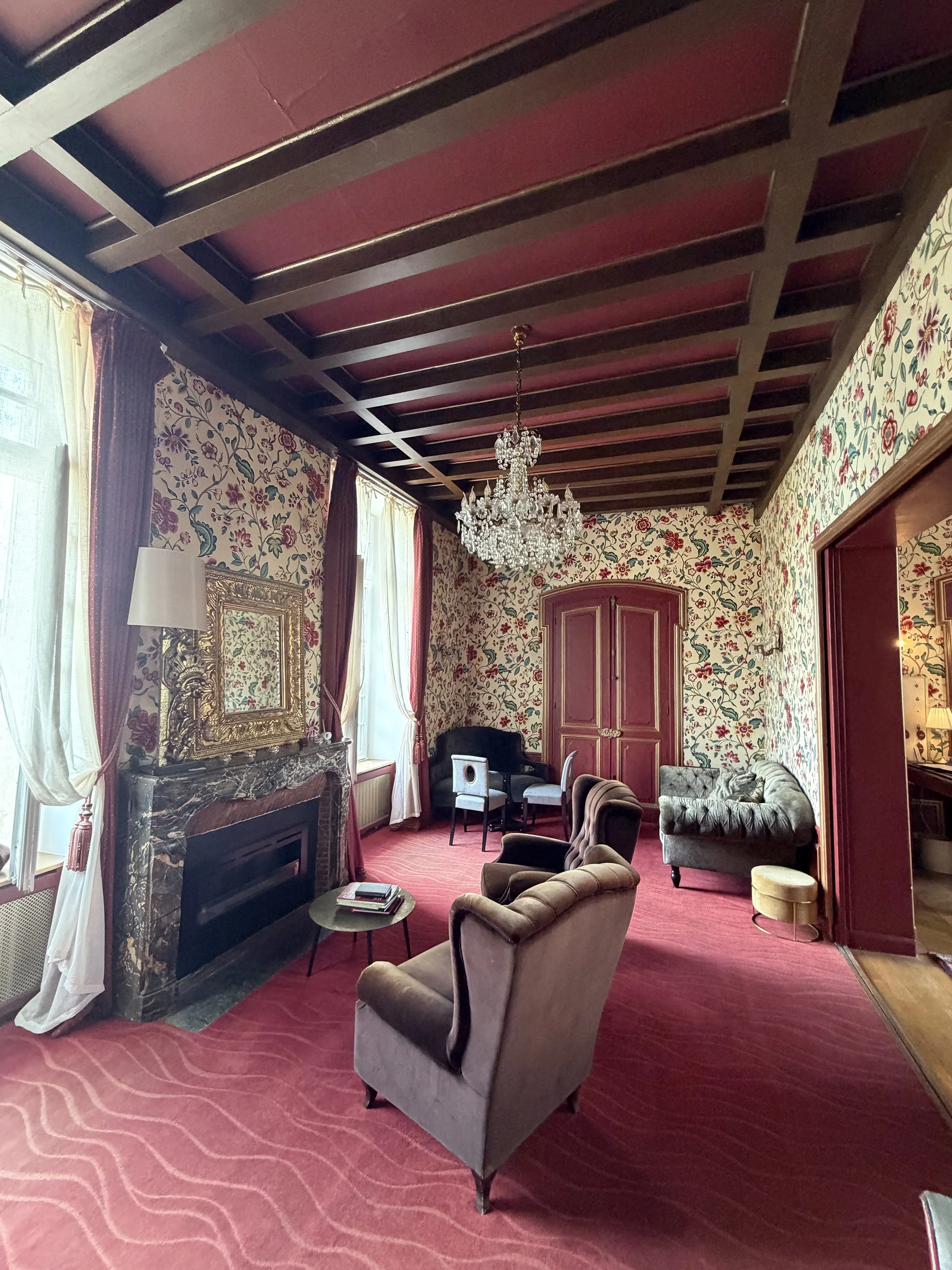 Elegant suite at Château de Fère with floral wallpaper, a crystal chandelier and a marble fireplace