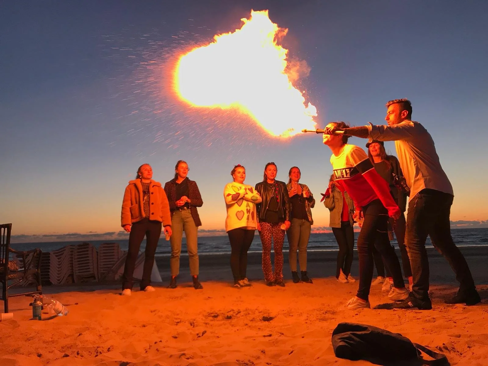 Een vuurspuwer voor een event op het strand in Zandvoort met werknemers eromheen