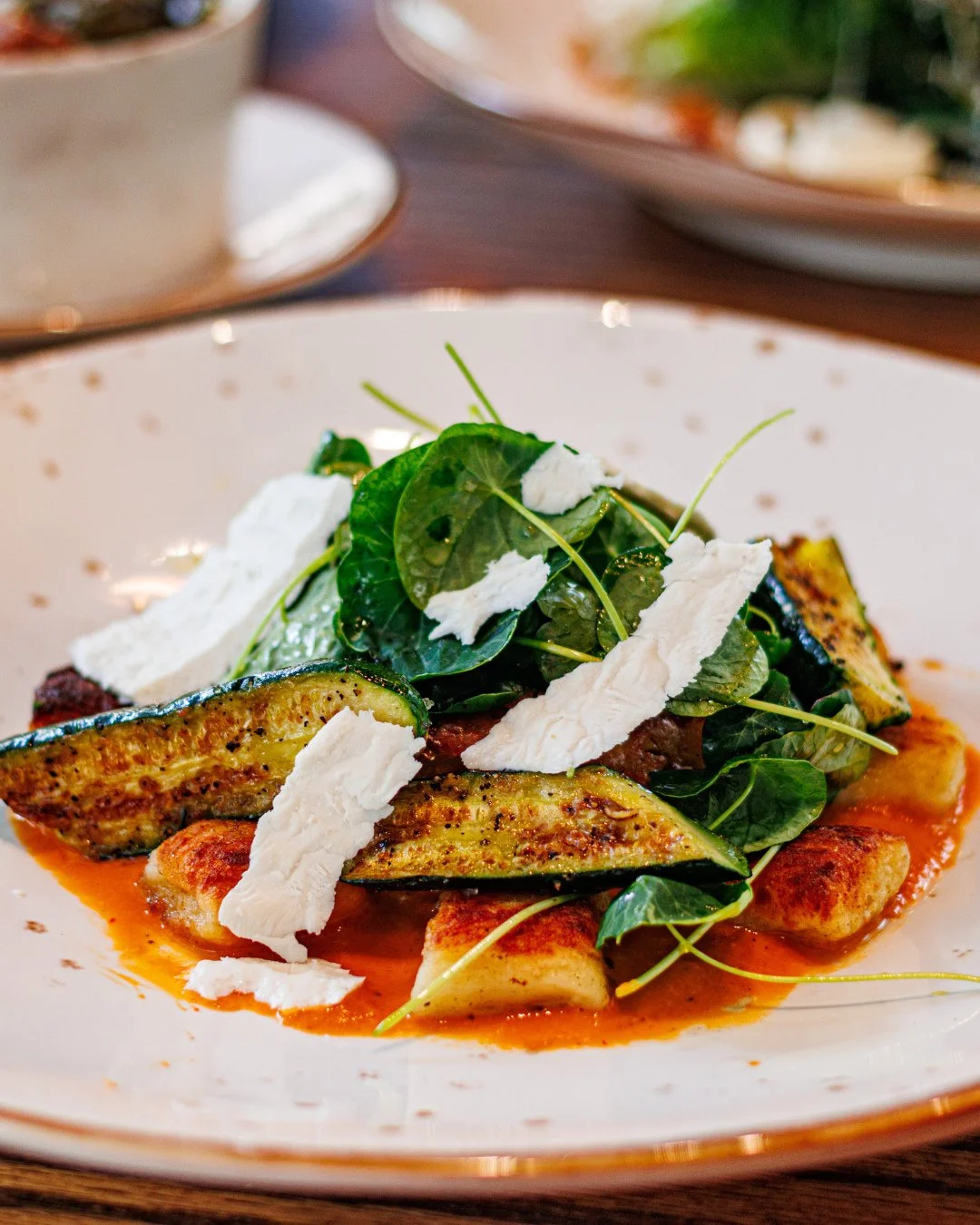 Peak-season flavors, just in time for summer&rsquo;s final stretch. House-made ricotta gnocchi with roasted corn cakes, baby squash &amp; heirloom tomato coulis.