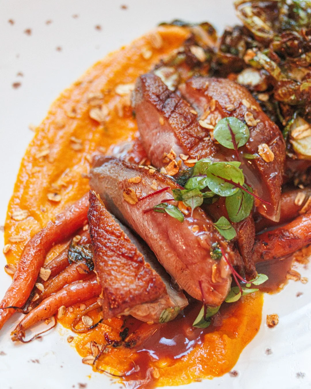 Pan-seared duck breast, creamy carrot pur&eacute;e, crisp Brussels, and a drizzle of pomegranate jus with a hint of cayenne crunch: it's yours to savor this week.