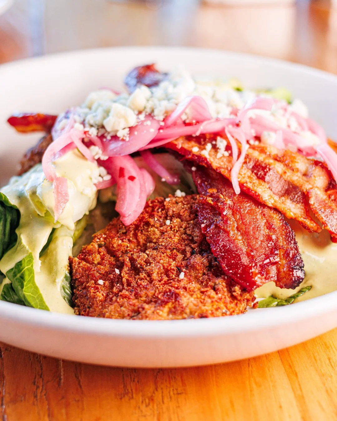 A wedge with a little more personality.🥓🍅🥬⁠
⁠
Fried green tomatoes, brown sugar bacon, blue cheese and green goddess dressing add a Southern flair to your classic lunch.