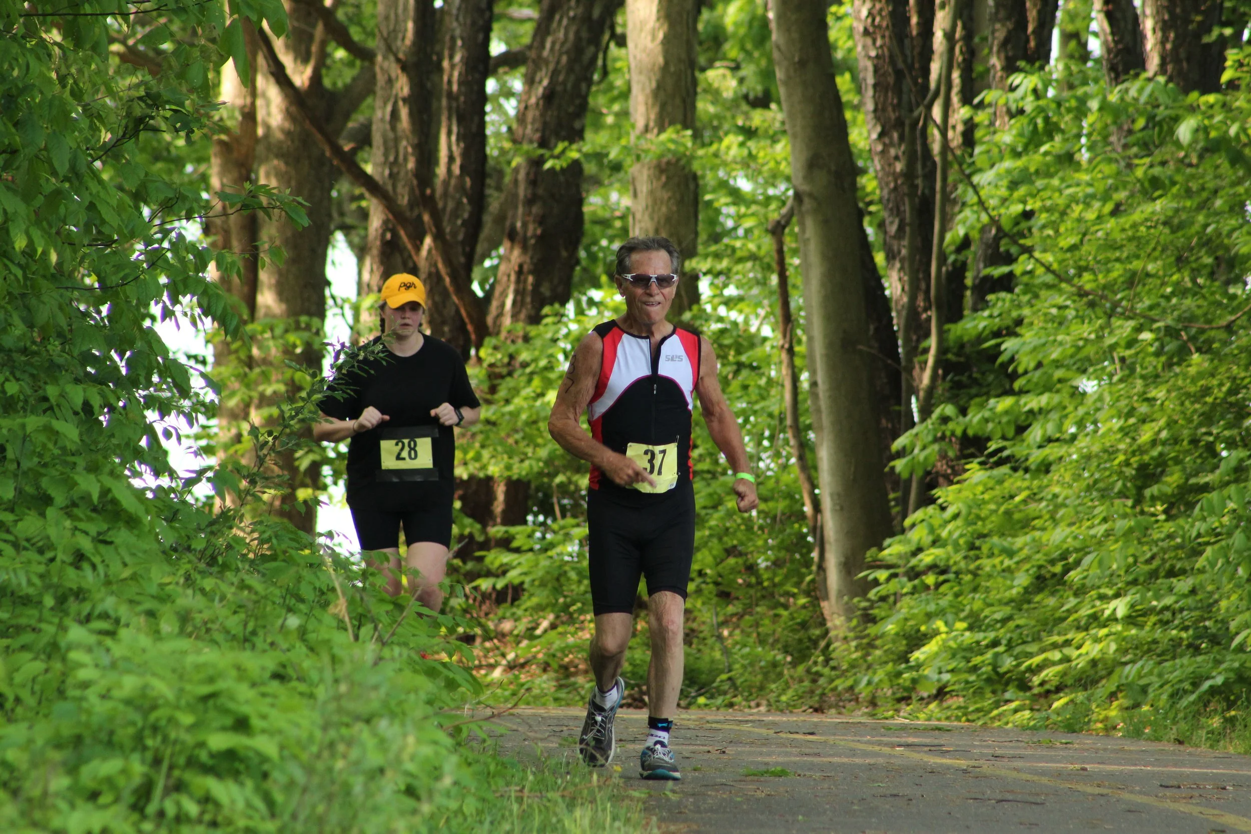Two athletes running on the wooded path at Mighty Moraine