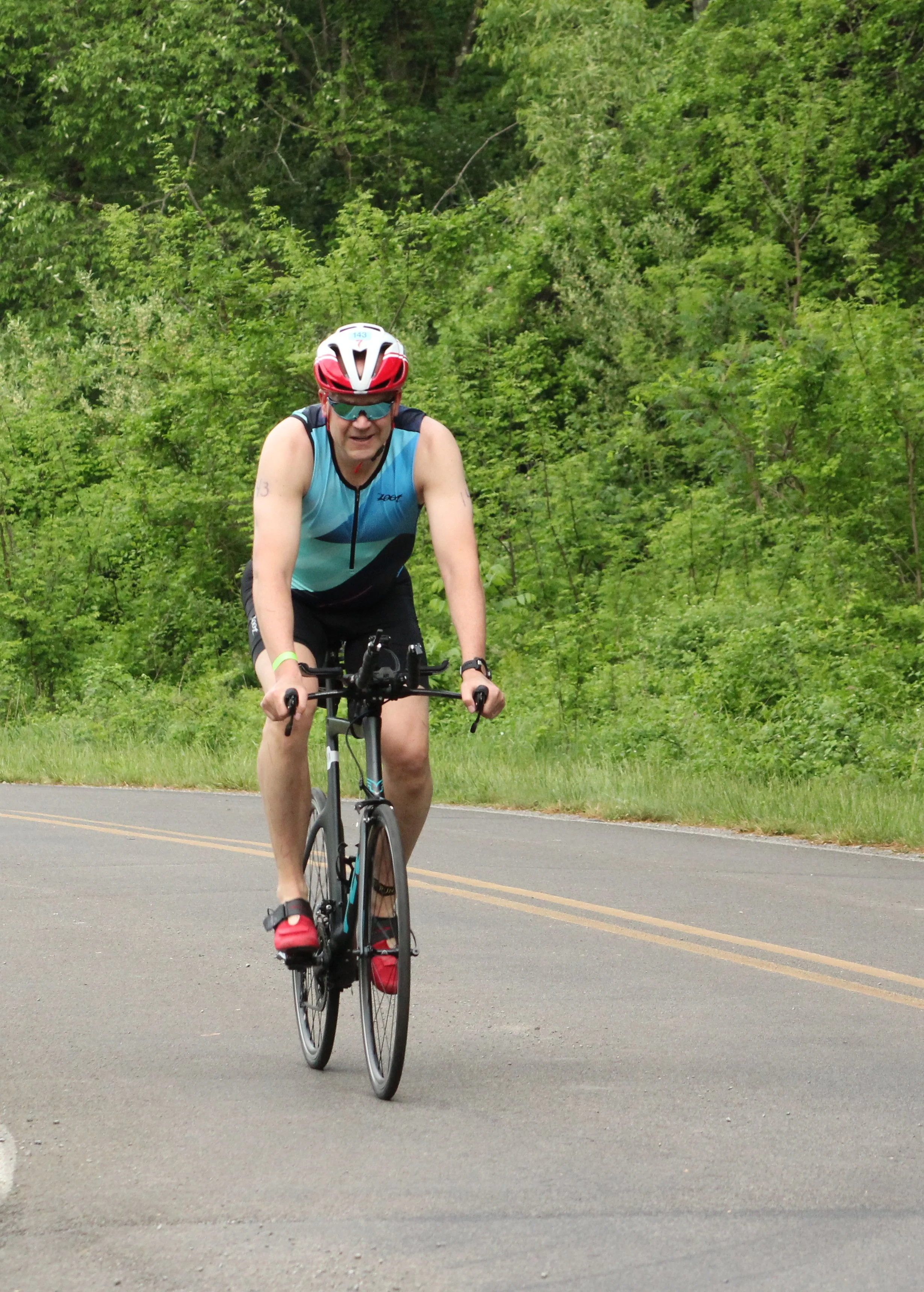 An athlete riding the bike course through the trees
