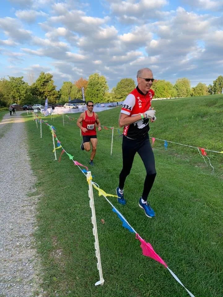 Two athletes running the grass course marked with flags