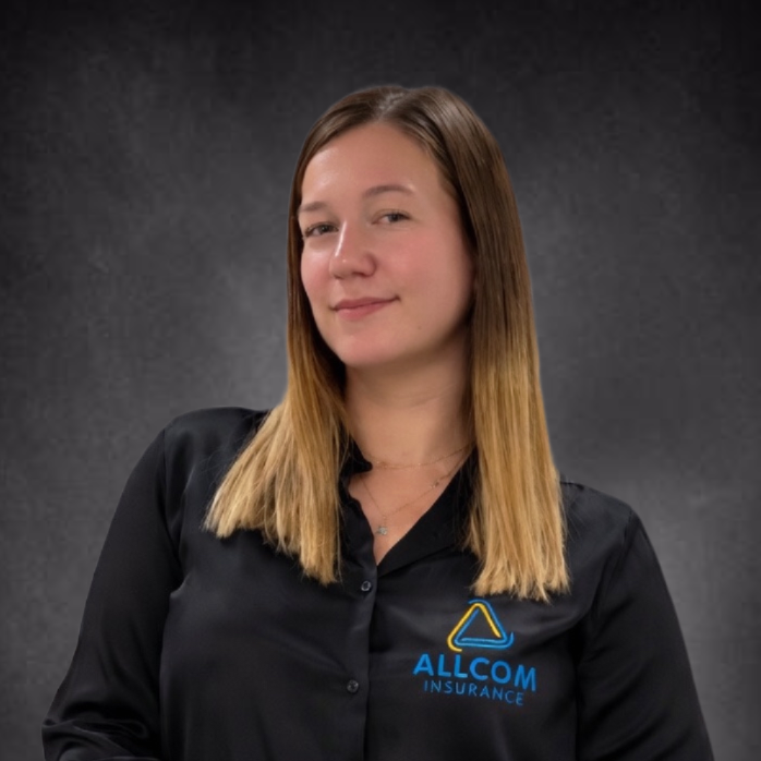 A young woman with long blonde hair, wearing a black button-up shirt with a blue and yellow Allcom Insurance logo, smiling slightly against a dark textured background.