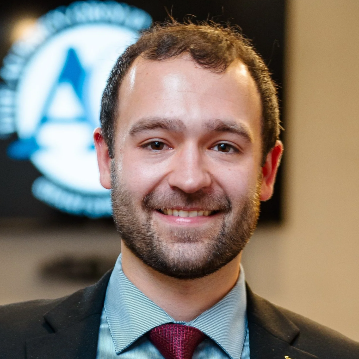 Man with brown hair and beard in a suit