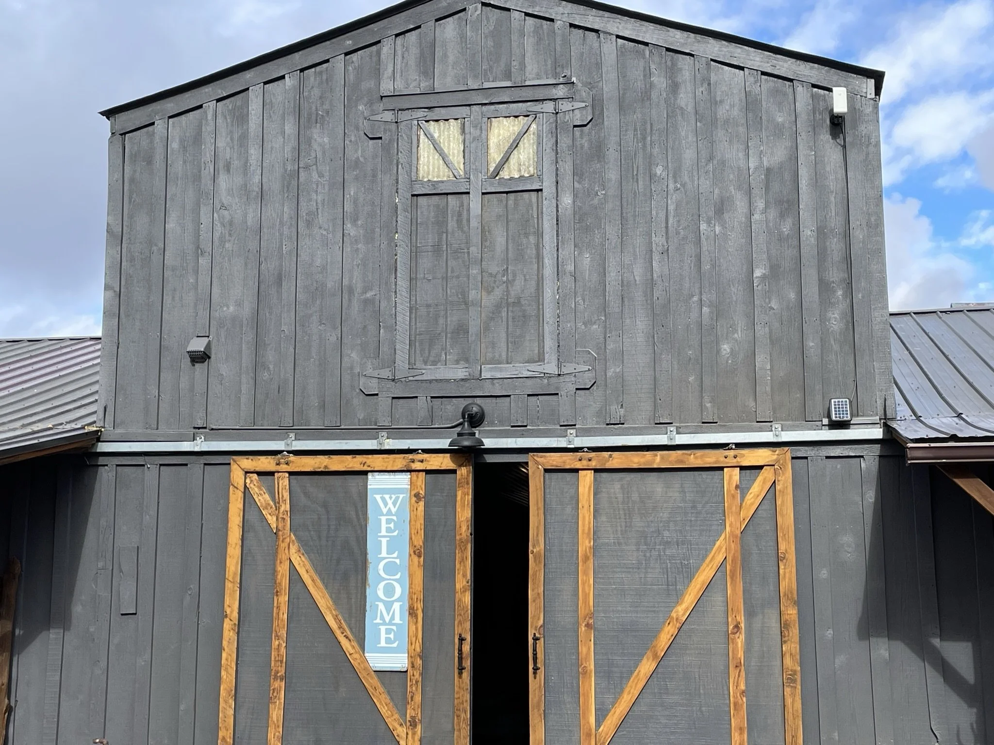 A barn with gray wooden siding and a wooden frame around the entrance displaying a