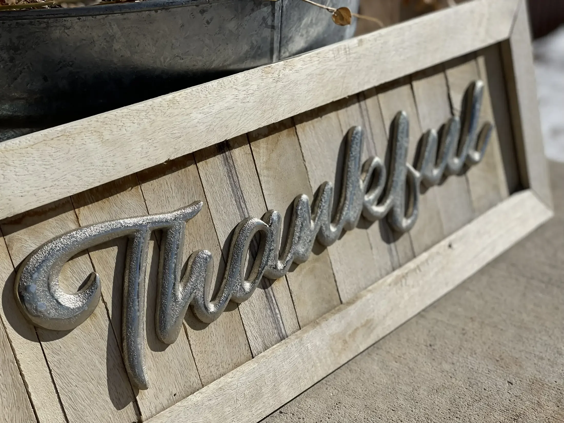 Close-up of a wooden sign with metallic letters spelling a word, mounted on a wooden surface.