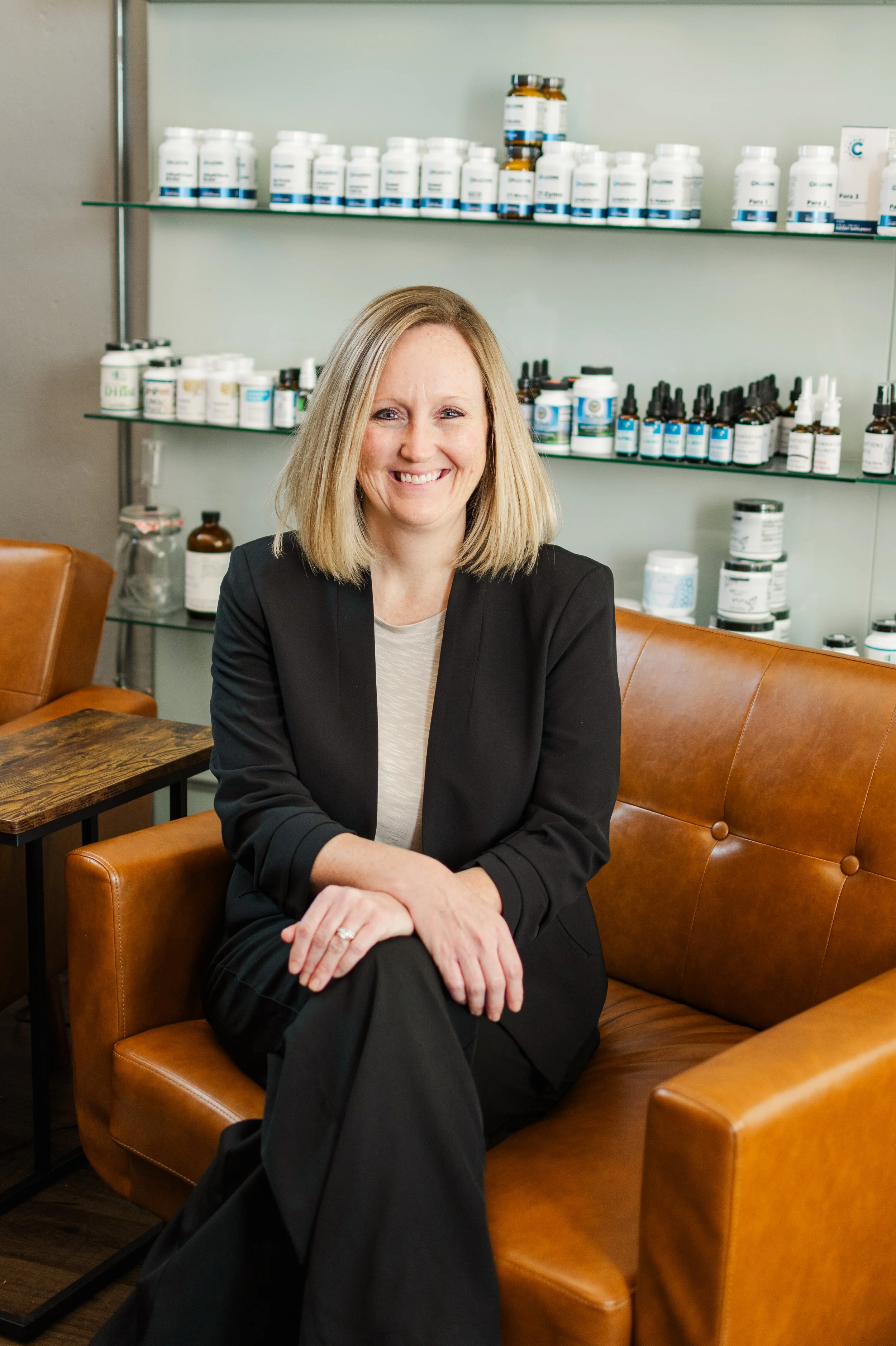 Woman seated in a brown leather chair in a room with shelves of health supplements.