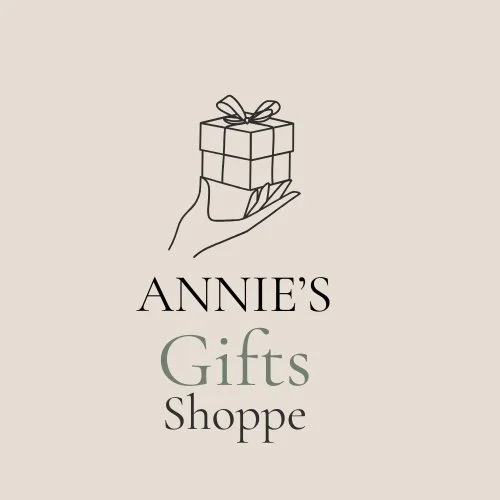Logo for Annie's Gifts Shoppe featuring a line drawing of a hand holding a wrapped gift box with a bow.