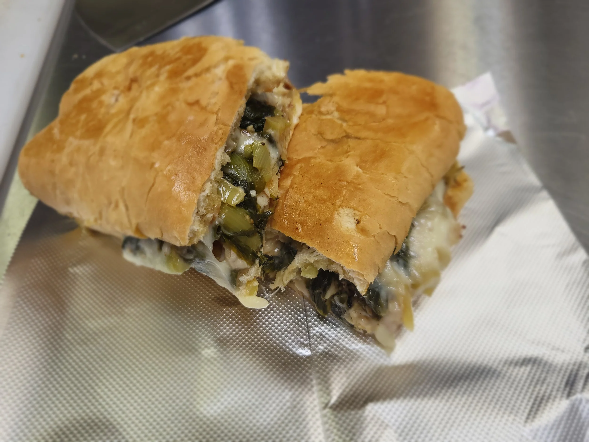 Kelly's Homemade Italian Greens on top of Grilled, Chopped & Seasoned Chicken Breast, with melted cheese, and nestled between toasted sub buns