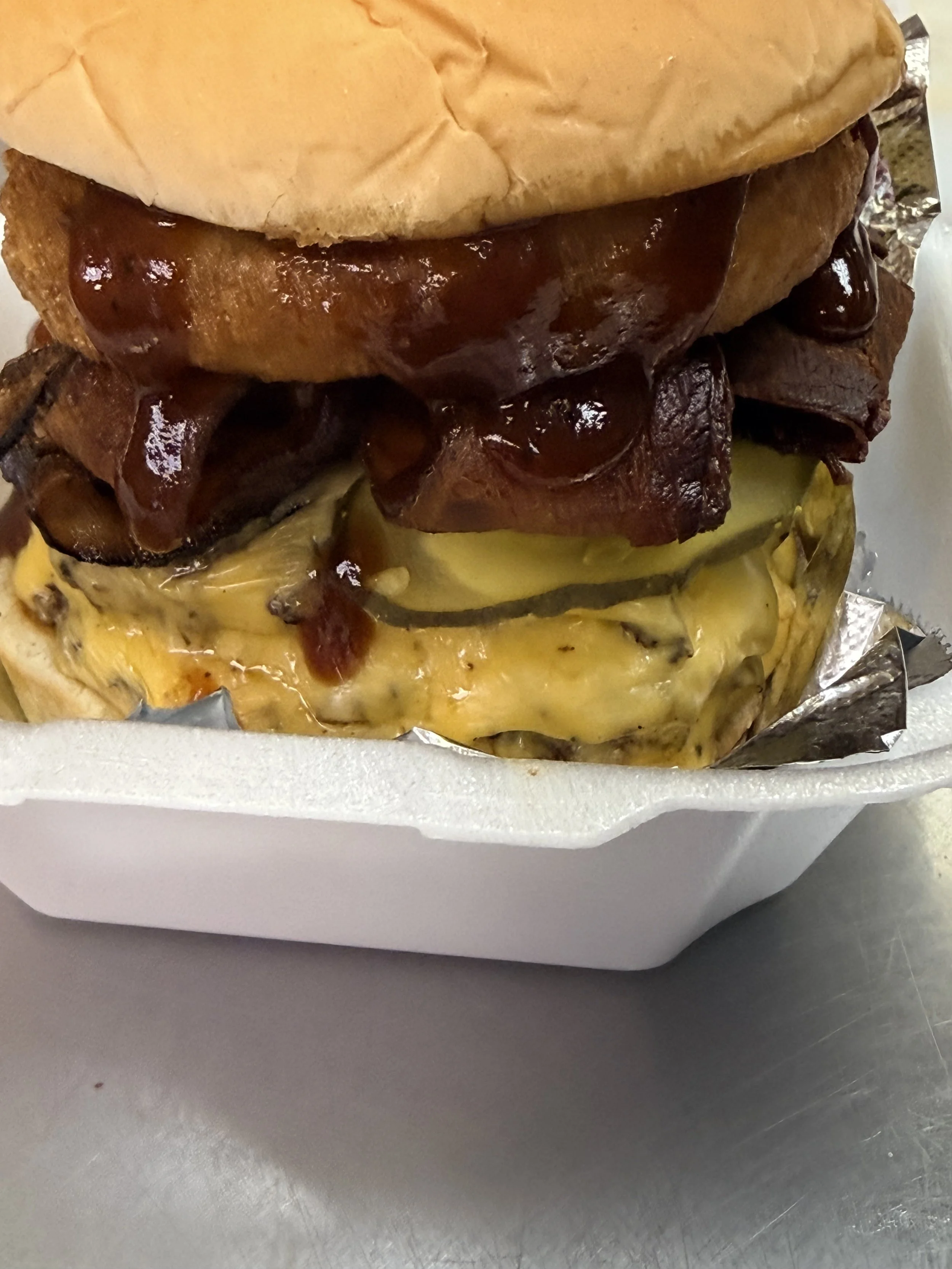 Cowboy Smash Burger
1/2 pound fresh pressed burger with bacon, lettuce, tomato, deep fried onion ring, and BBQ sauce between a toasted bun. Yeehaw!