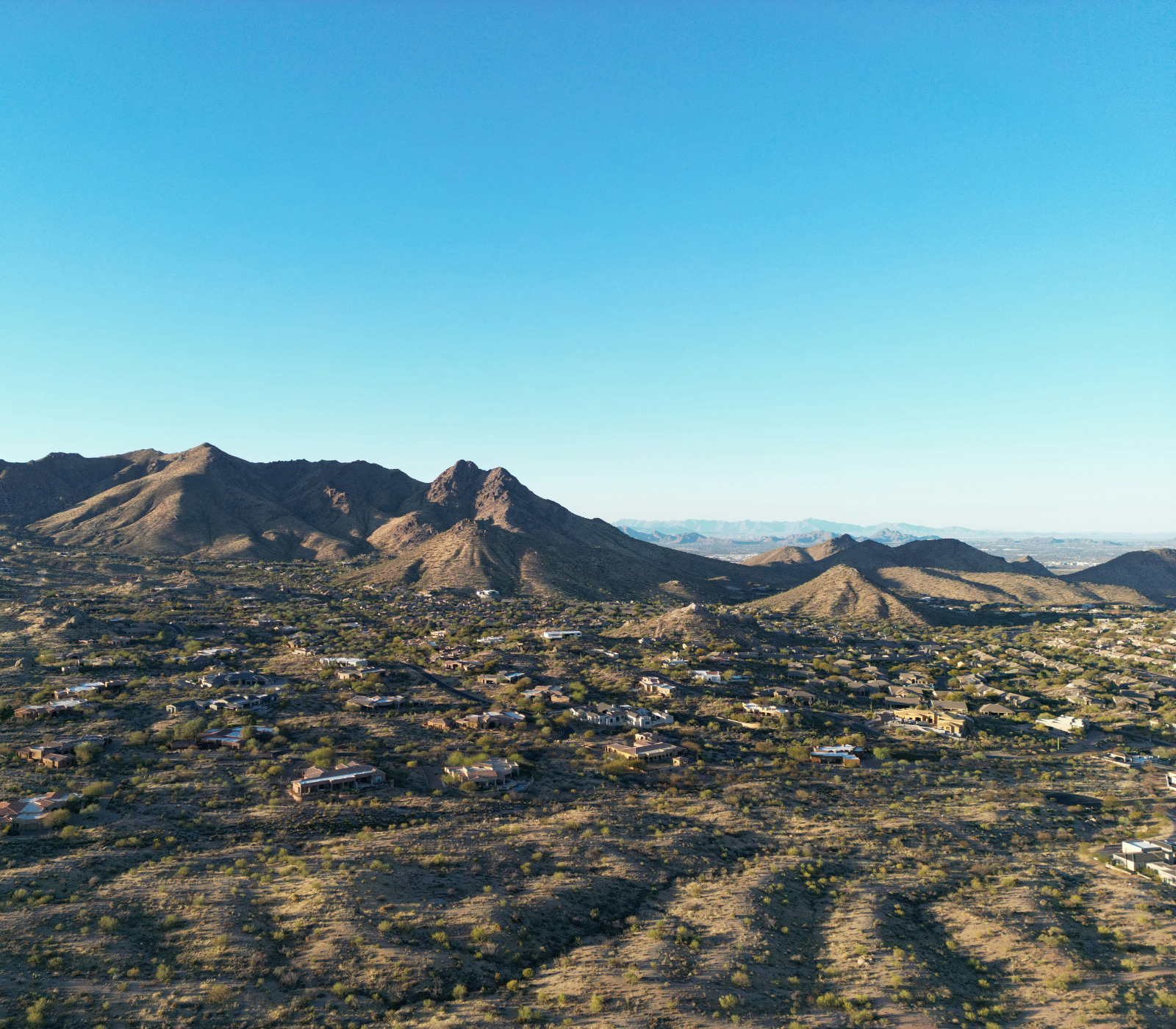 Aerial view of residential properties and roads in desert terrain in Scottsdale, Arizona.
