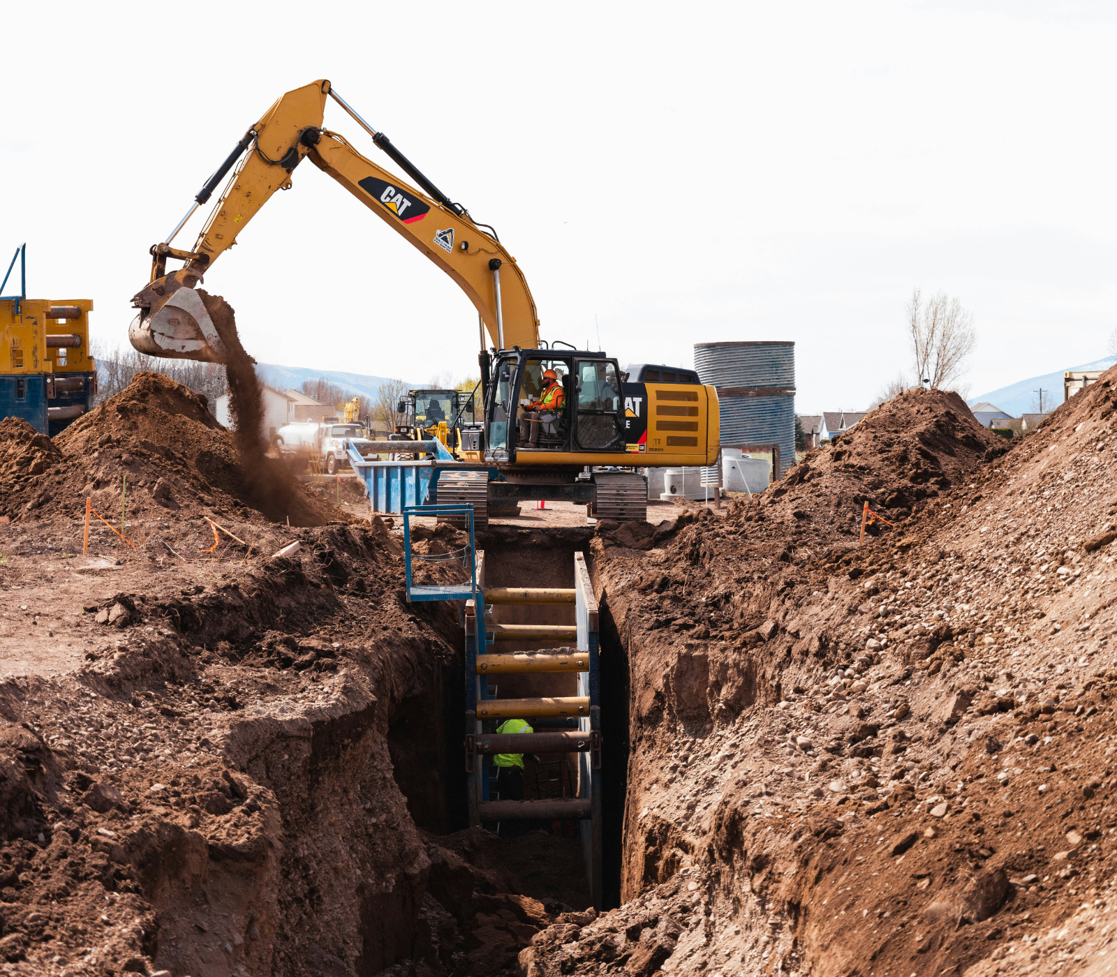 Excavator digging into soil during site work for a septic repair or replacement project.