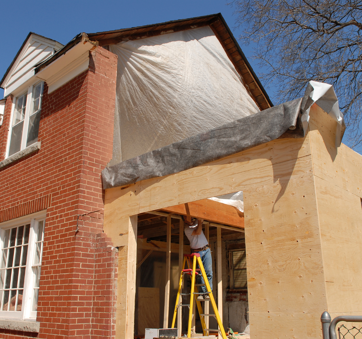 Home addition under construction beside an existing brick house