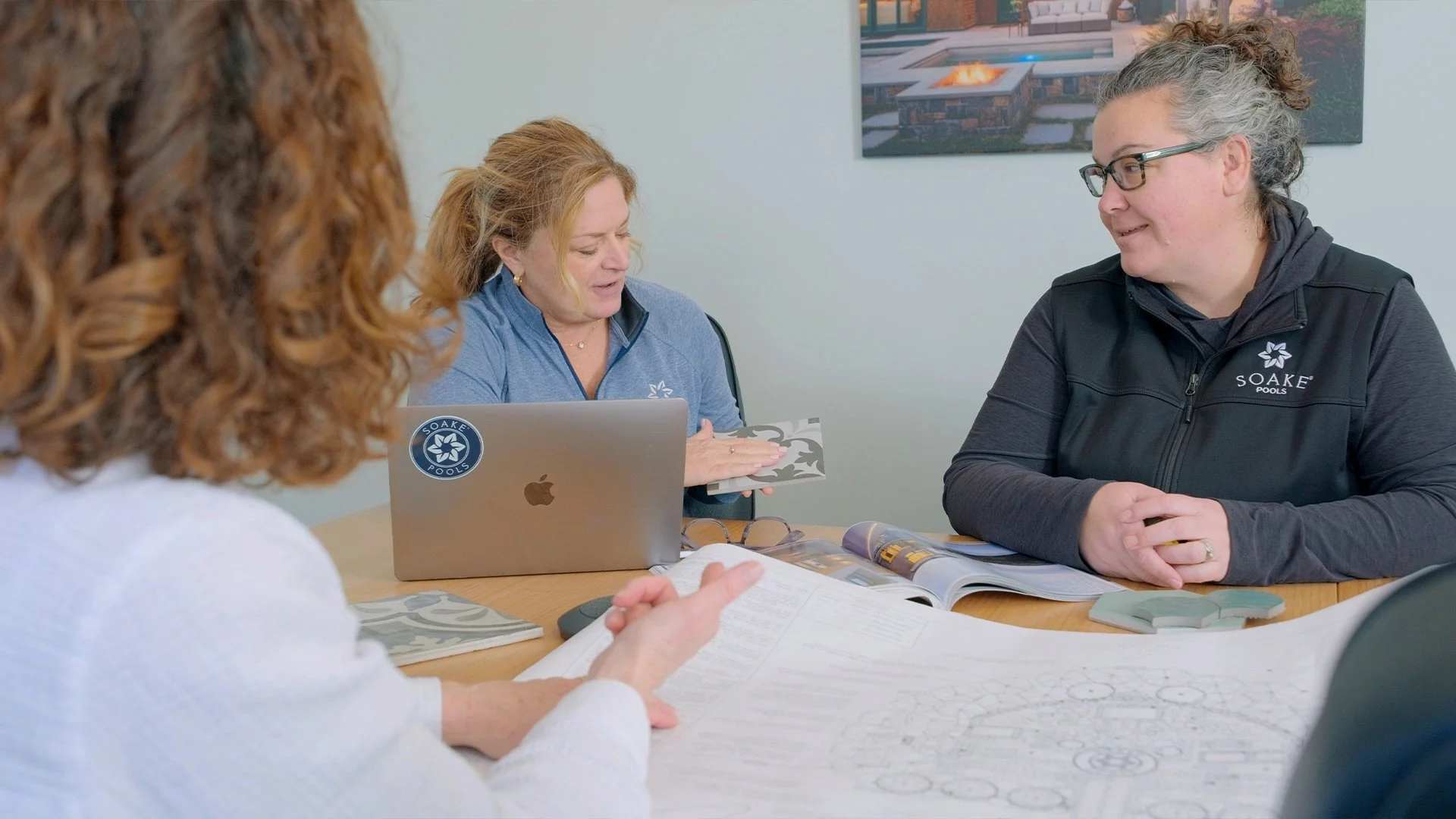 Soake Pools design team reviewing tile options and plans for a small pool and hot tub combo with a customer during the design process.