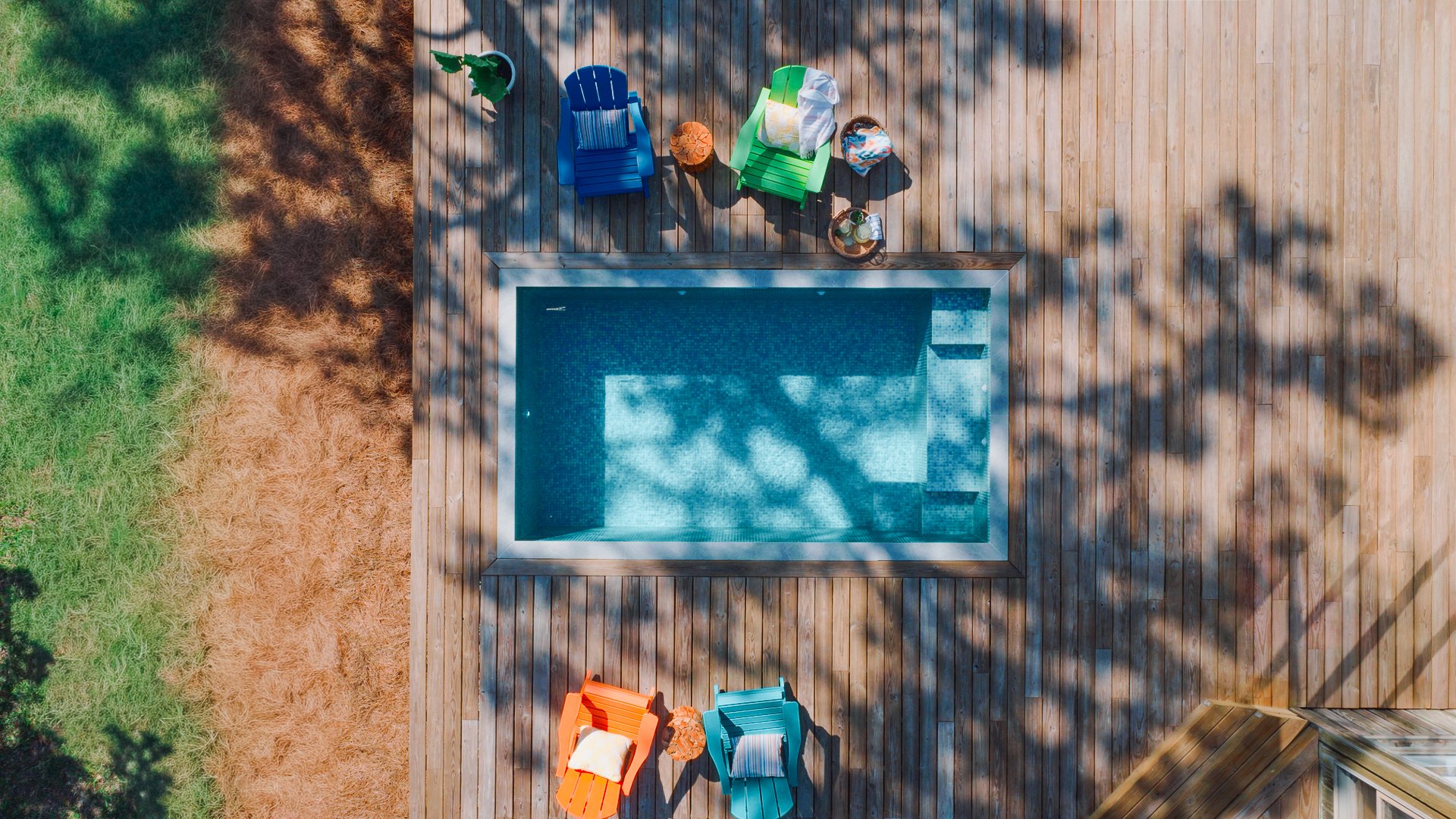 COLORFUL CHAIRS AND A CUSTOM MOSAIC-TILED SMALL POOL SURROUNDED BY DECKING CREATE AN EASY, INVITING BACKYARD RETREAT ON HILTON HEAD ISLAND.