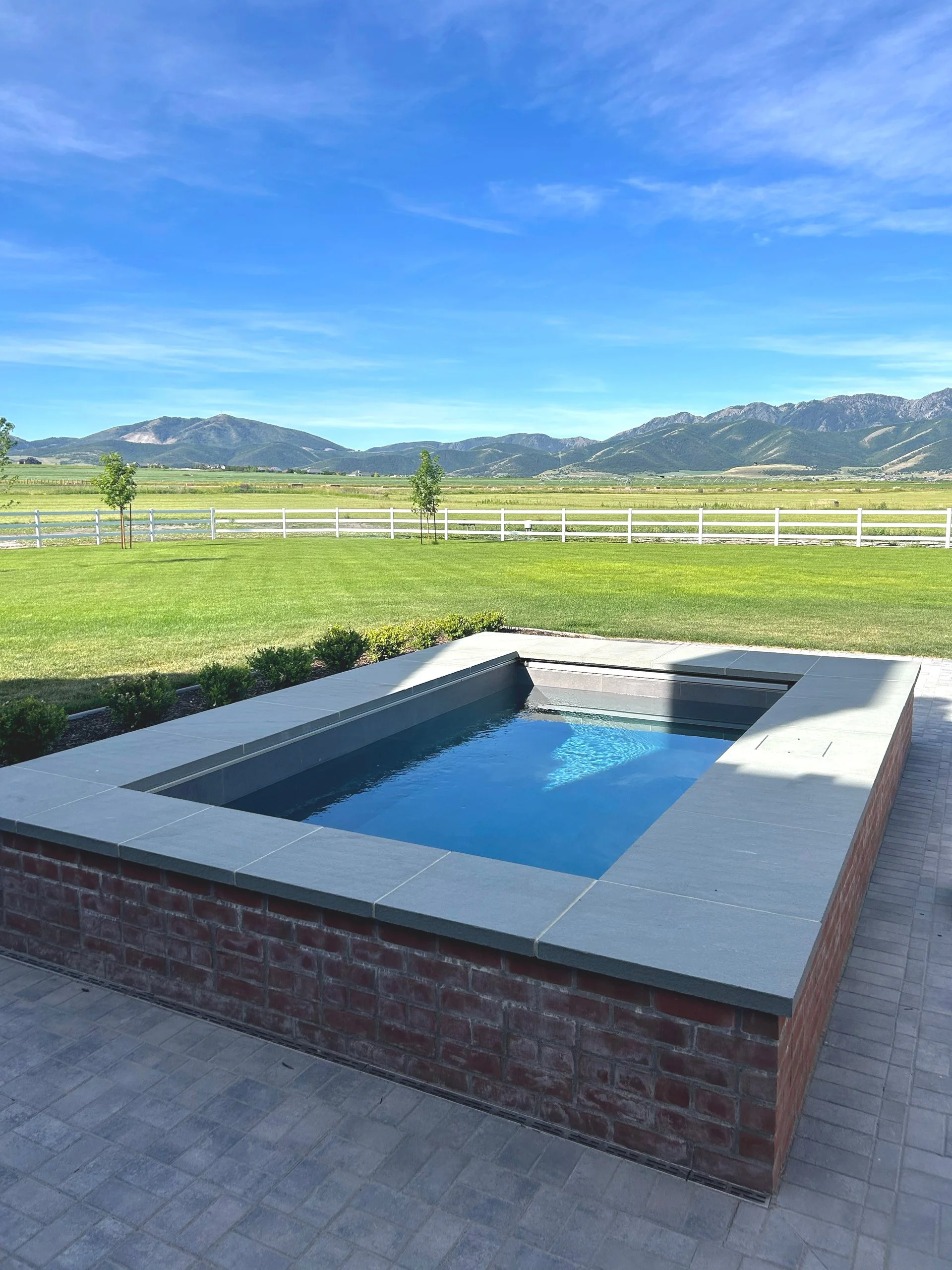 TIMELESS BRICK COPING FRAMES THIS SOAKE POOL WITH UTAH MOUNTAIN VIEWS.