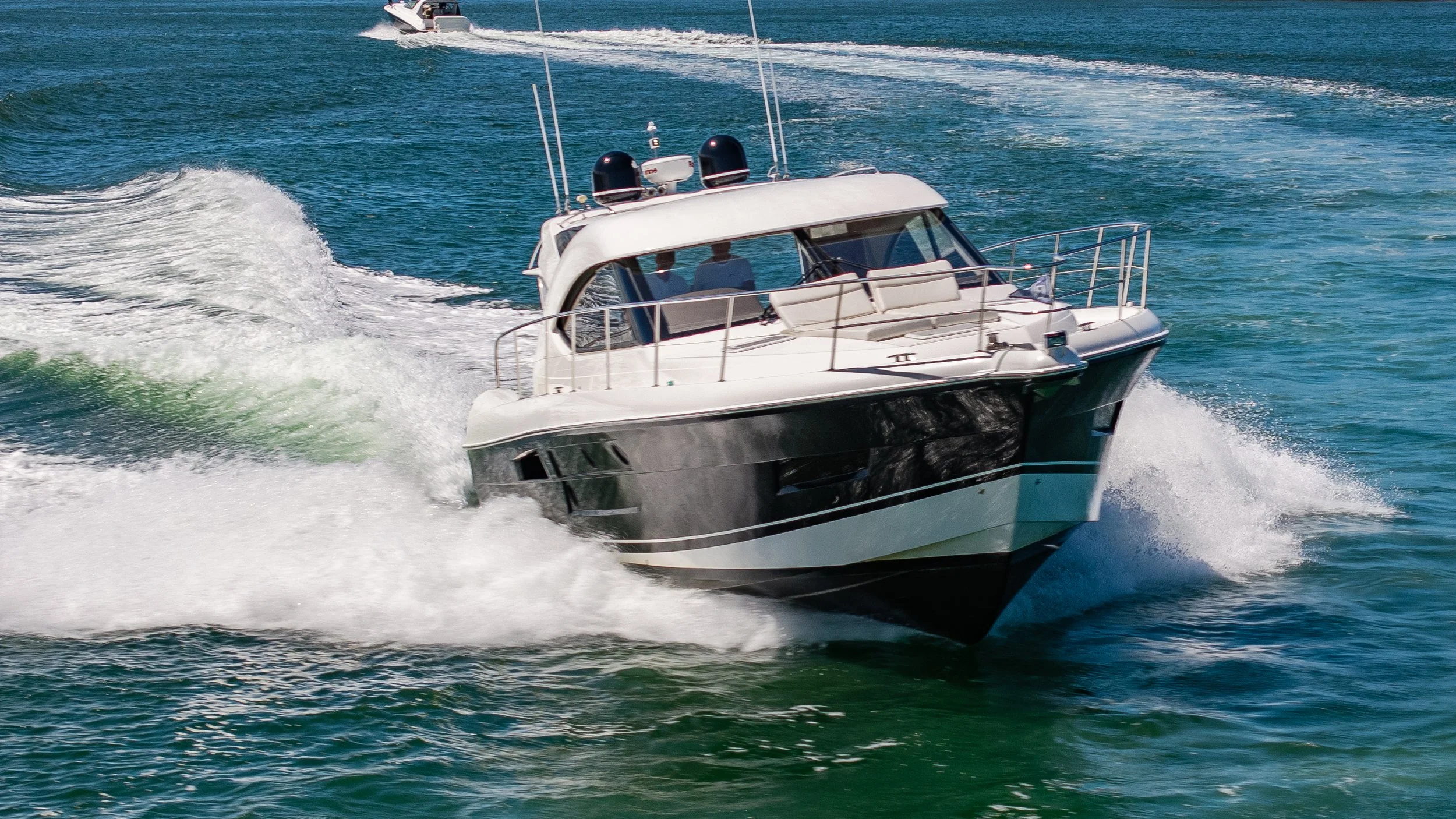 A motor yacht cruising swiftly on the water, creating white wake.