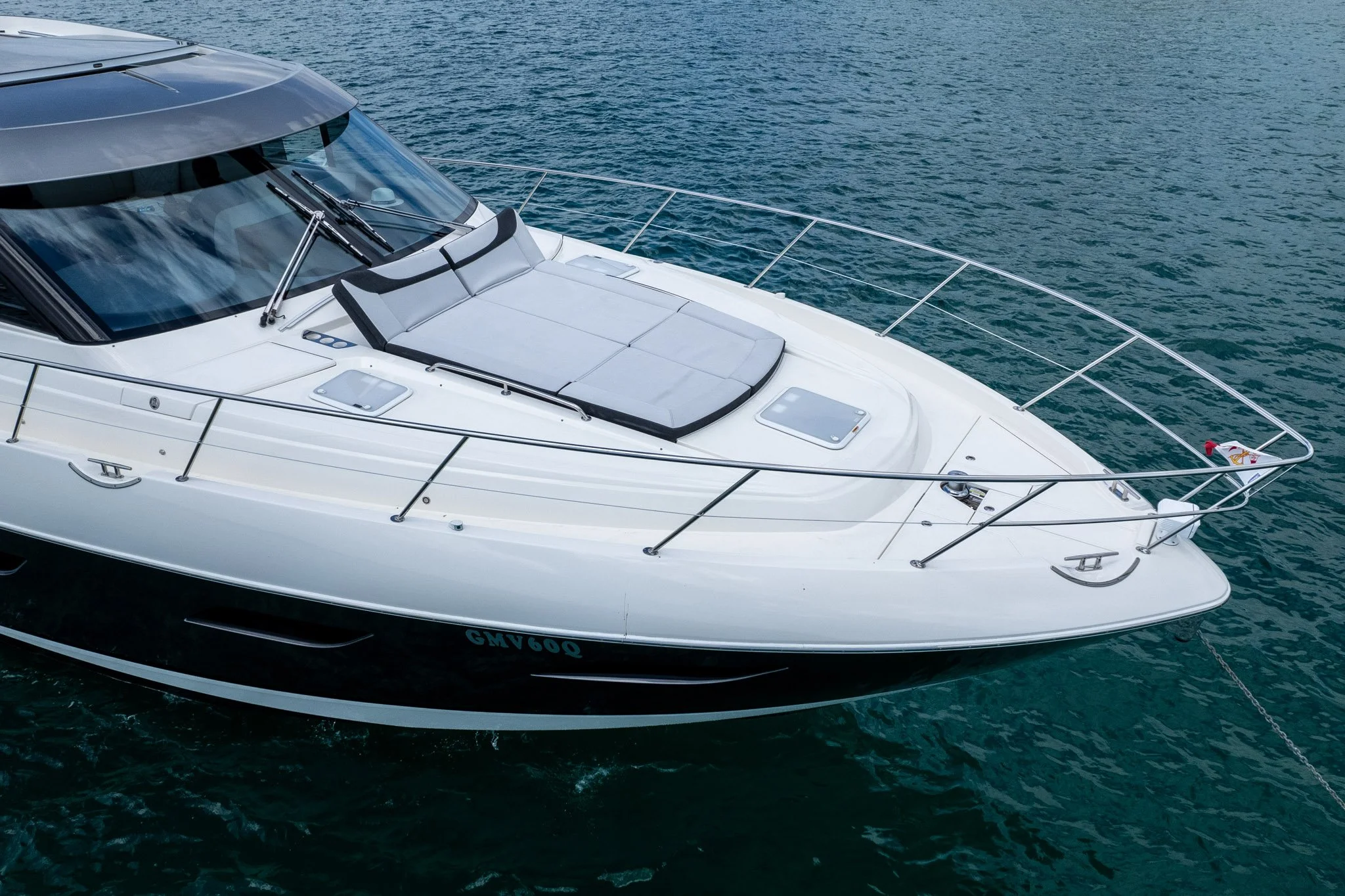 Large white yacht floating on calm ocean water, viewed from above.