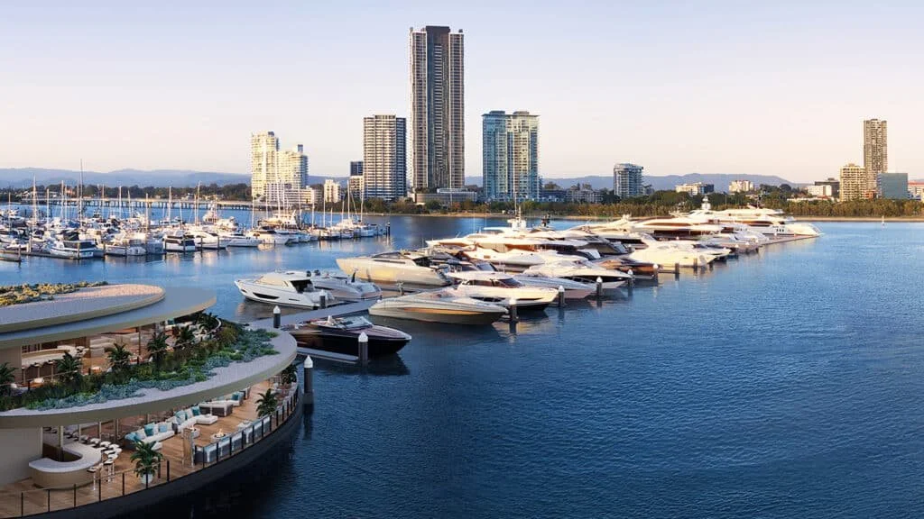 A marina filled with luxury yachts and boats, with a large white building and tents behind it, overlooking the ocean with a cloudy sky.