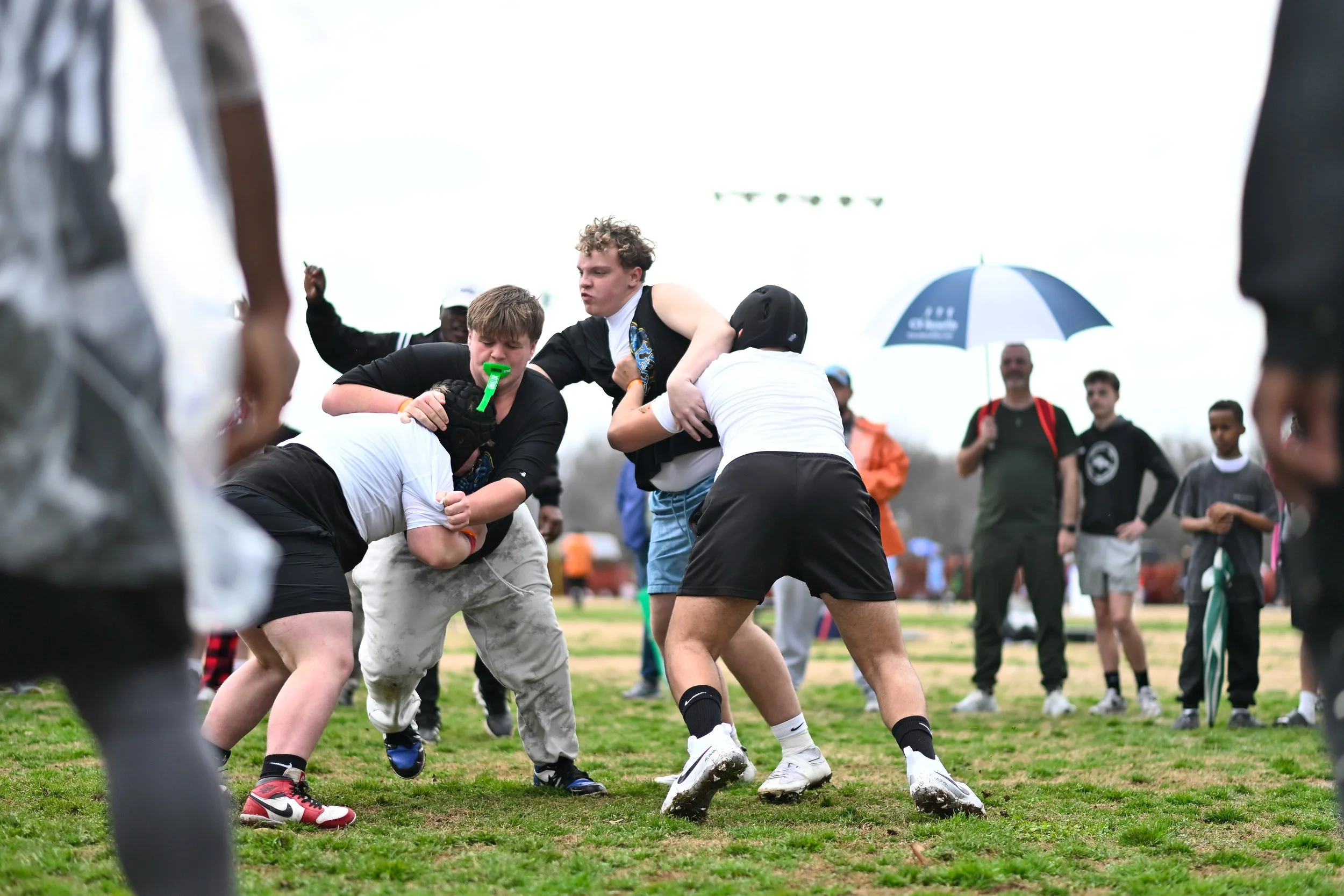 Young people engaging in a game of flag football outdoors, with onlookers watching.
