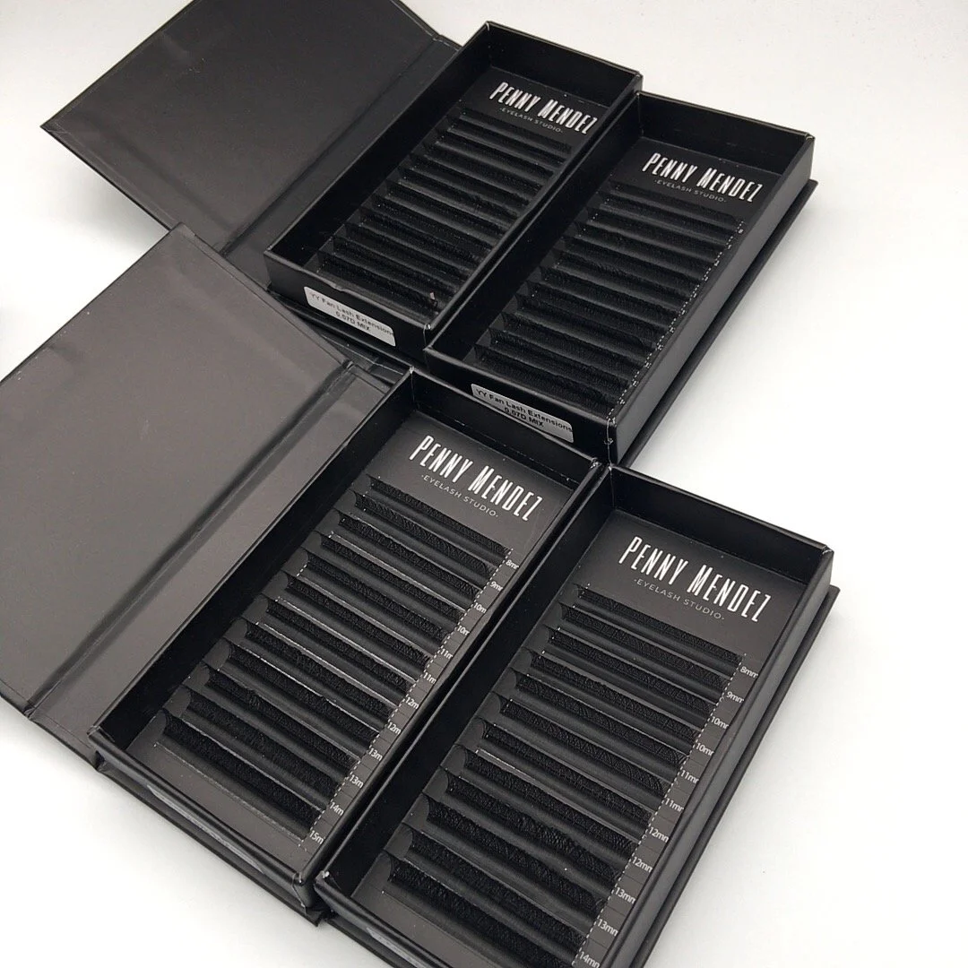 Tres cajas negras de pestañas postizas de diferentes tamaños con la marca Penny Mendel Eyelash Studio.
