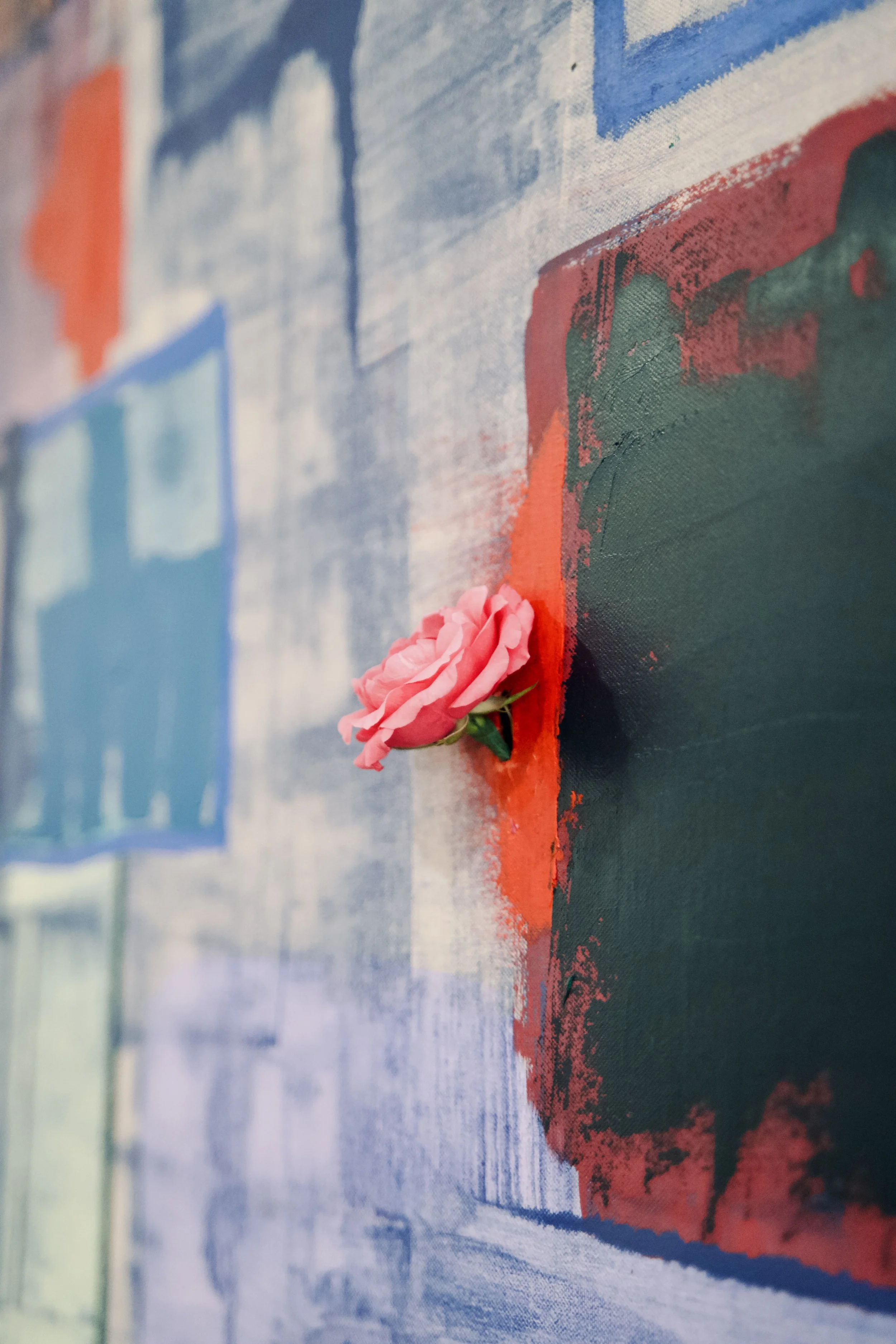 Pink ribbon placed on a colorful abstract painted canvas.
