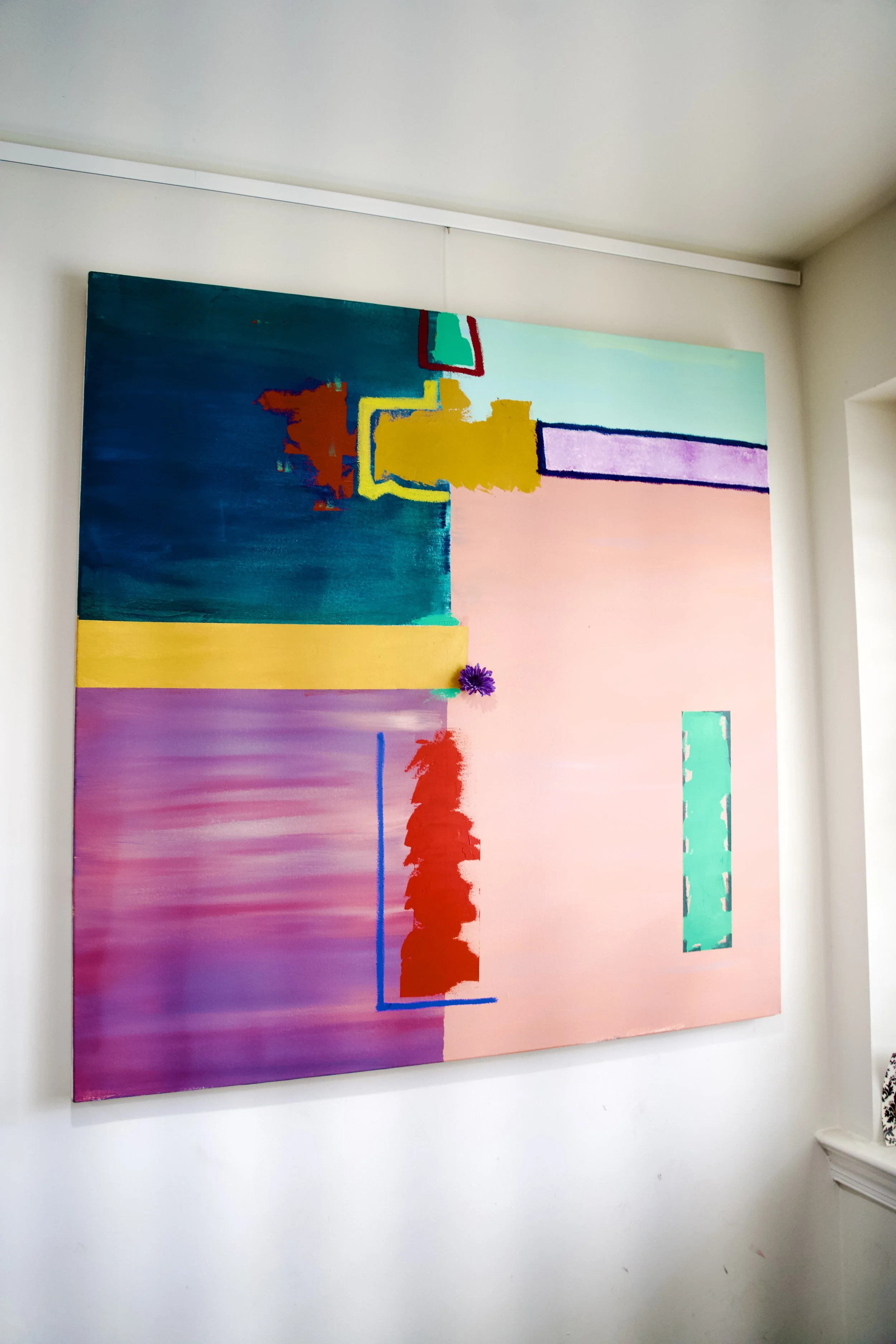 Abstract colorful painting on a white wall with various shapes, colors, and lines.