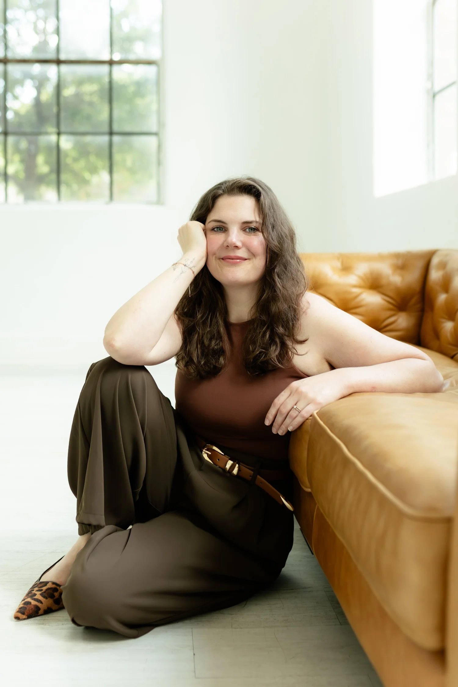 Alyssa Simpson, founder of Restfully Rich, seated beside a sofa