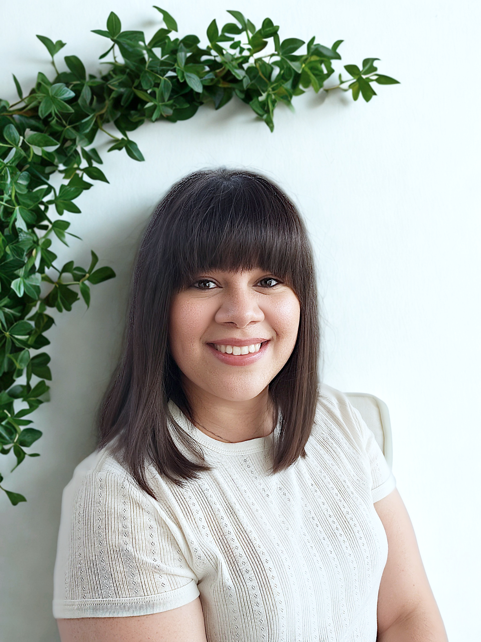 This is another picture of Brittney Guembes, LPC, a therapist at Heart of Texas Therapy Services who specializes in treating anxiety and OCD. She has a warm smile and is standing under some greenery..