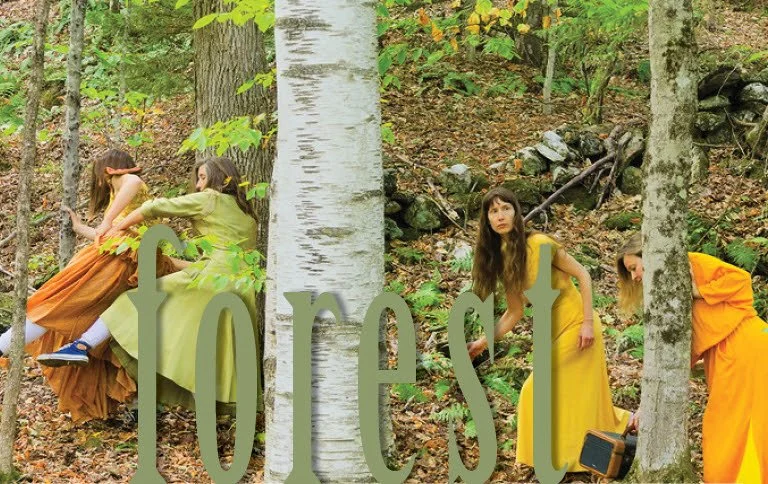 4 dancers in yellow and orange dresses moving through a northern forested area