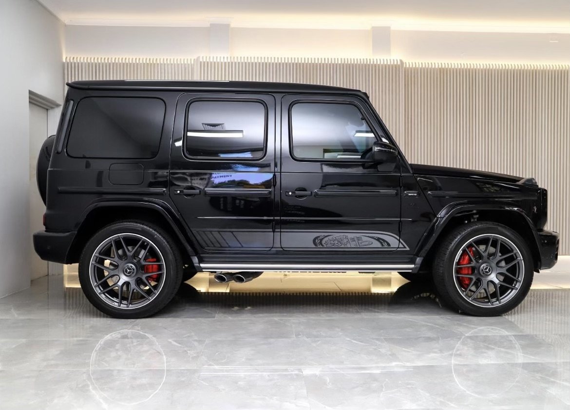 Black luxury SUV parked in a showroom with alloy wheels and red brake calipers, side view.