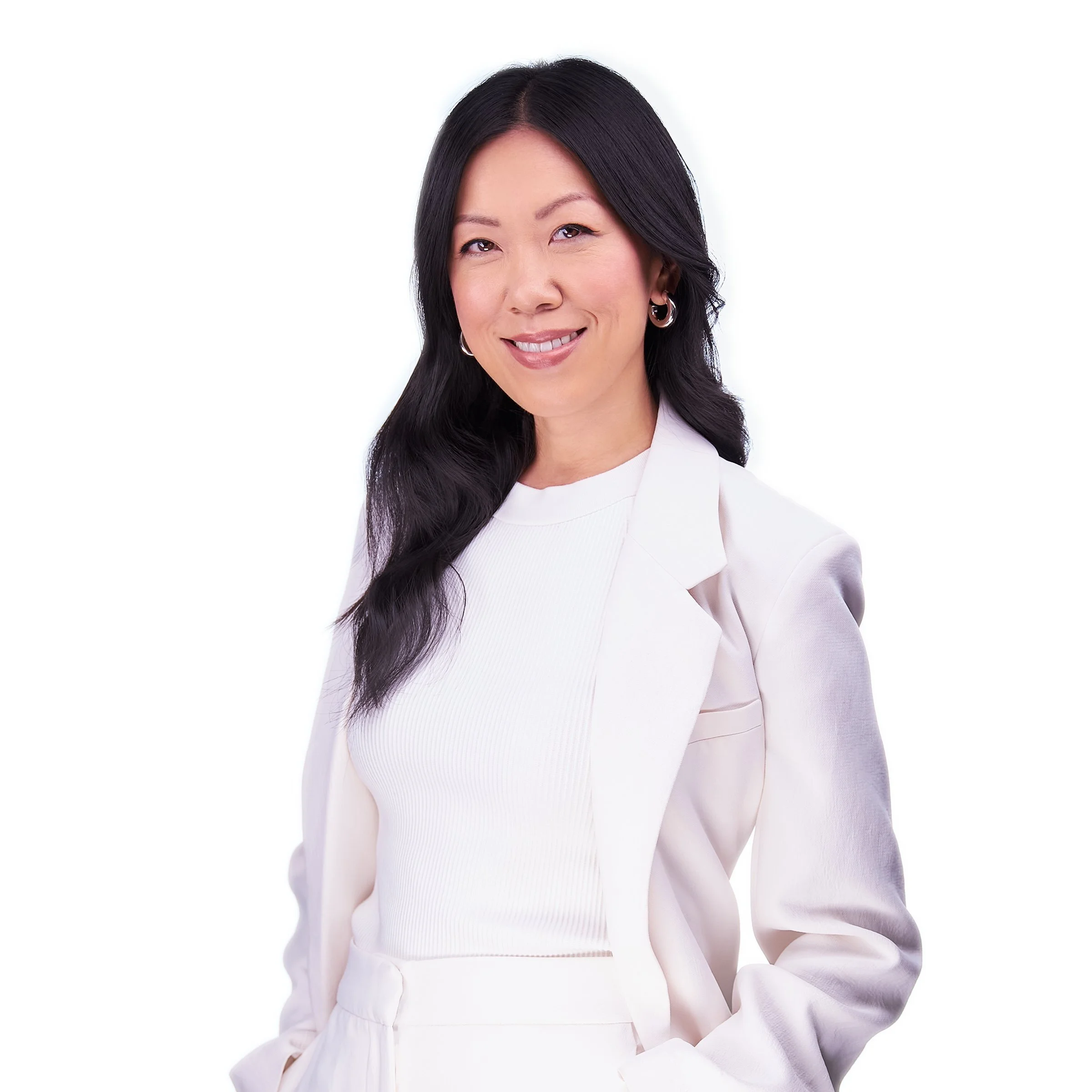 A woman with long black hair, wearing a white blazer and matching top, smiling at the camera against a white background.