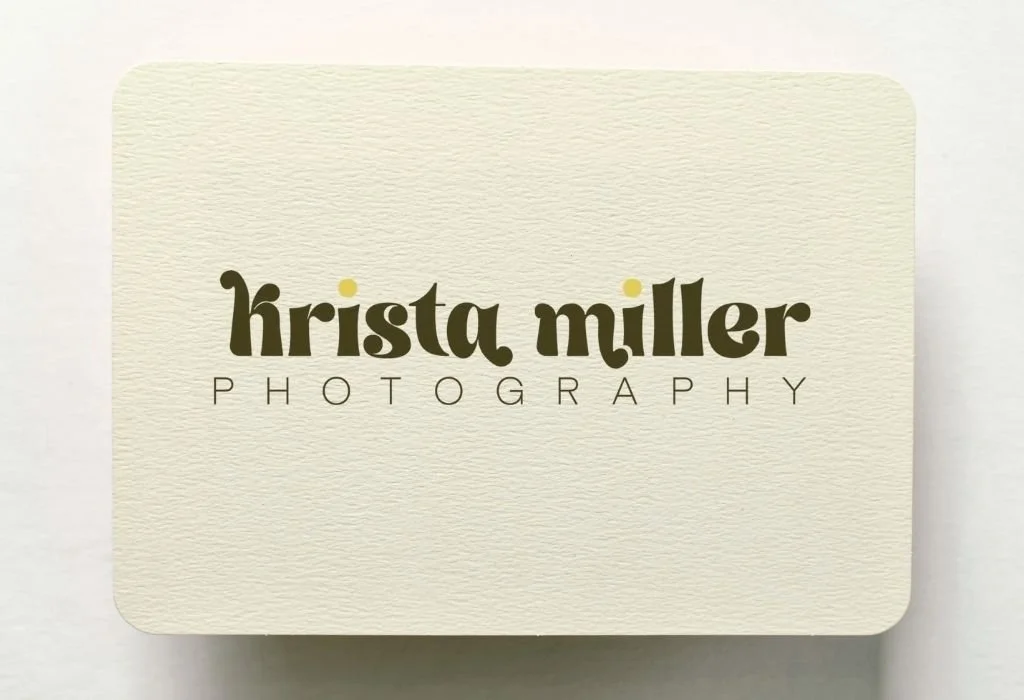 Business card for Krista Miller Photography with a cream textured background and stylized black and yellow text.