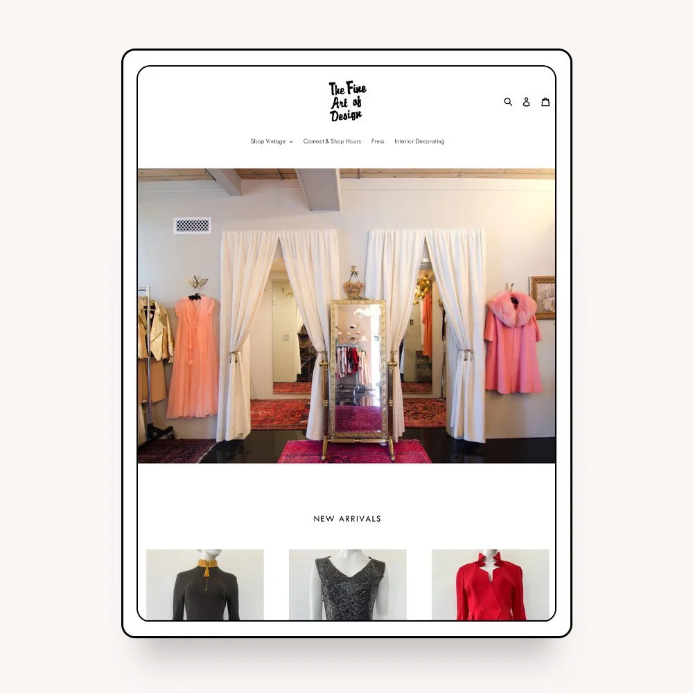 A boutique clothing store interior with dresses on display, including pink and peach gowns, framed mirror, and clothing racks, viewed through a website on a tablet screen.